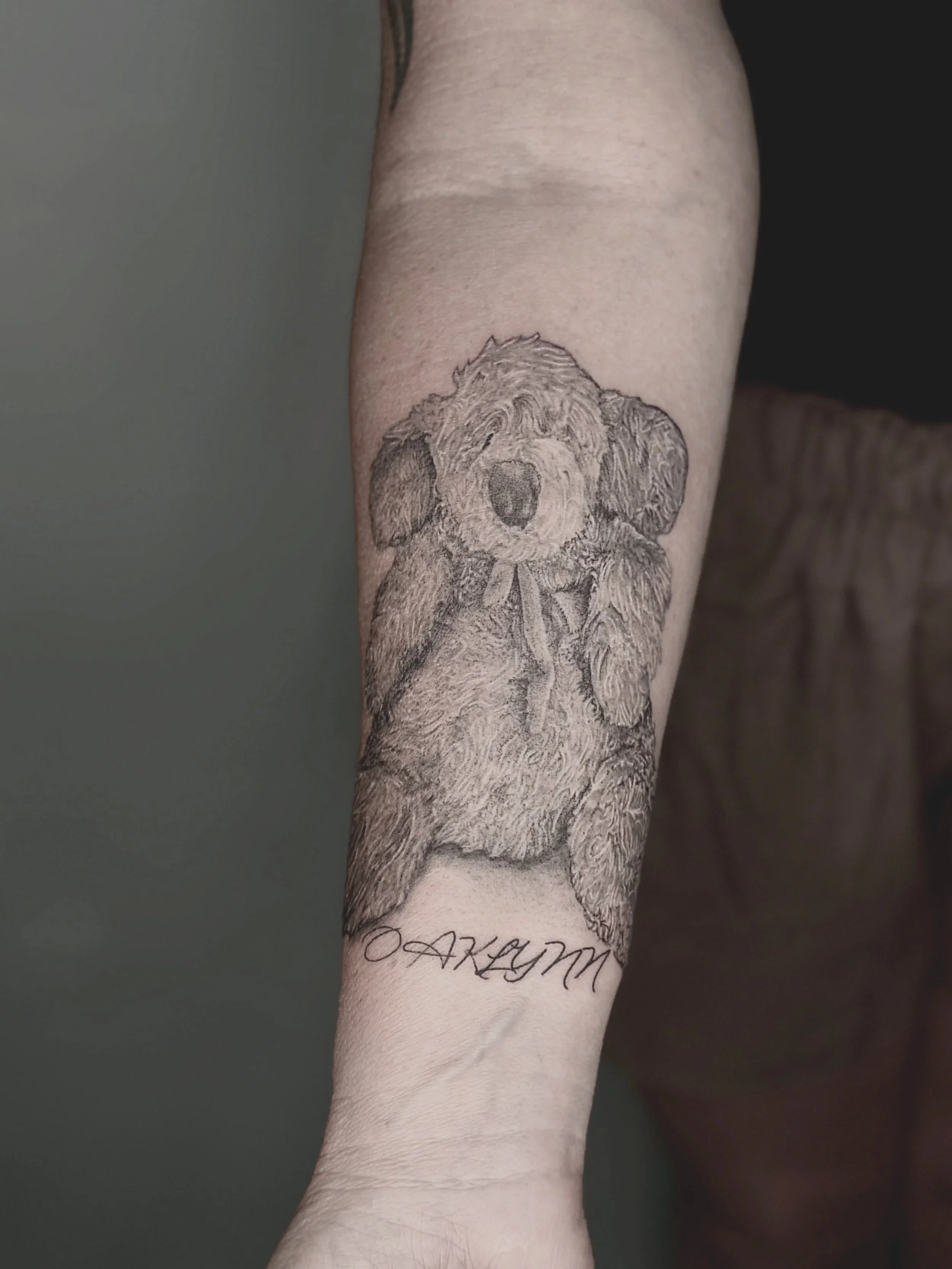 Tattoo of a cute, detailed dog with floppy ears and a bow on the arm