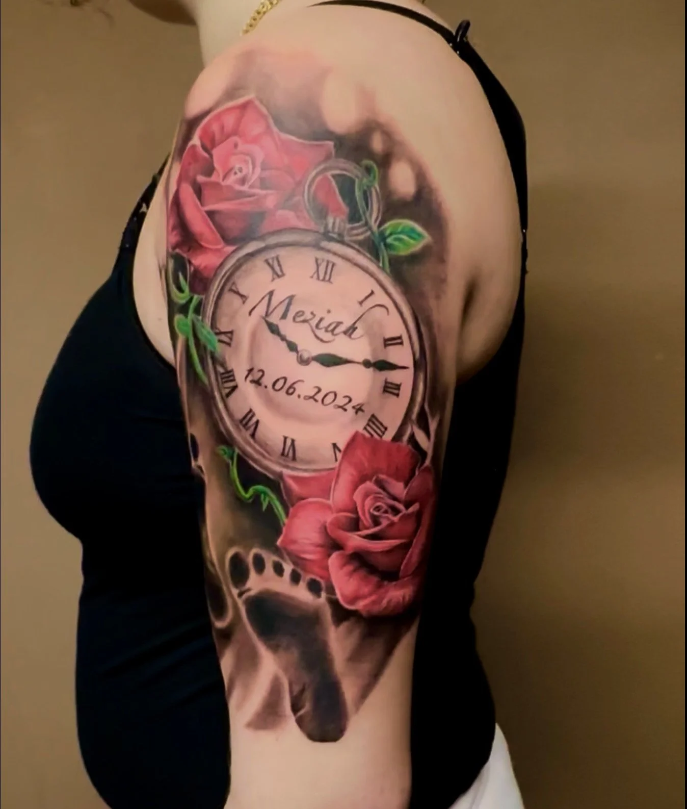 Tattoo of a pocket watch with the name 'Meziyah' and date '12.06.2024' inside the watch face, surrounded by pink roses and green leaves.