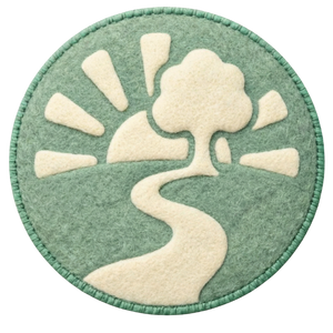 A circular embroidery patch featuring a stylized landscape with a tree, a winding path, and a sun with rays, in green, cream, and off-white colors.