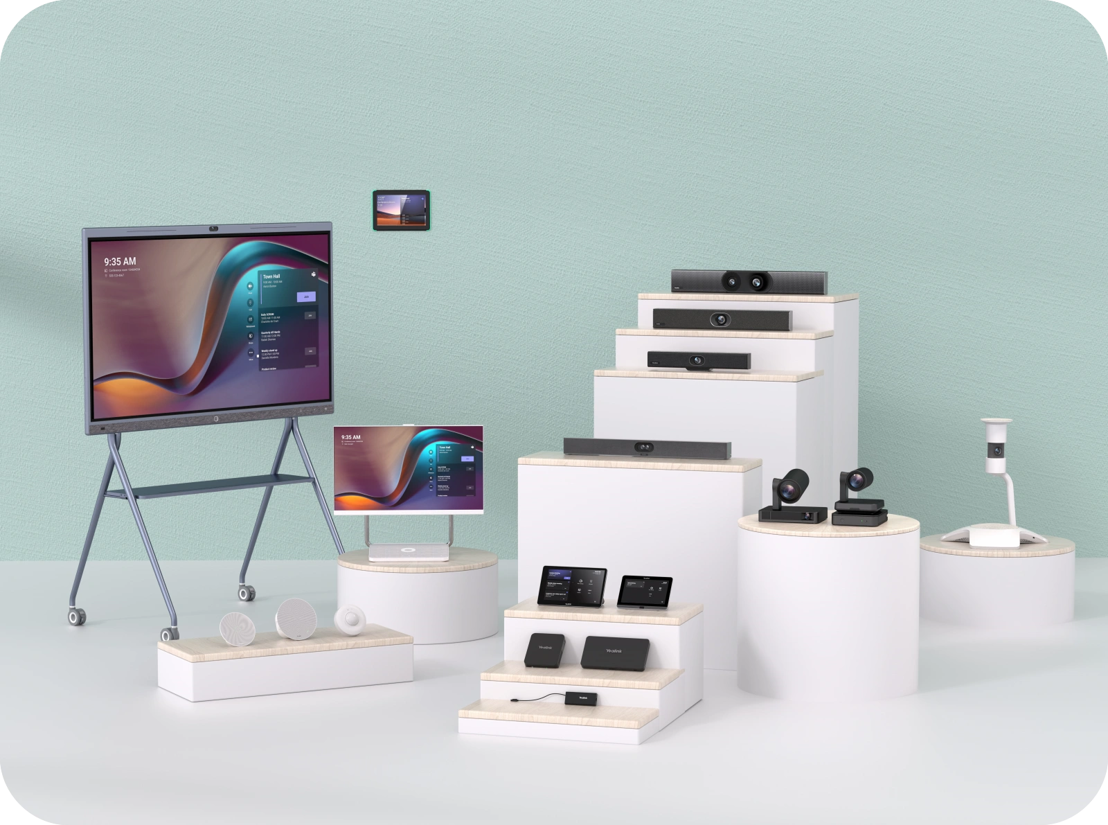 Display of various electronic devices including a large monitor on a stand, a smaller monitor, tablets, smart speakers, and video conferencing equipment on white pedestals in a studio setting.