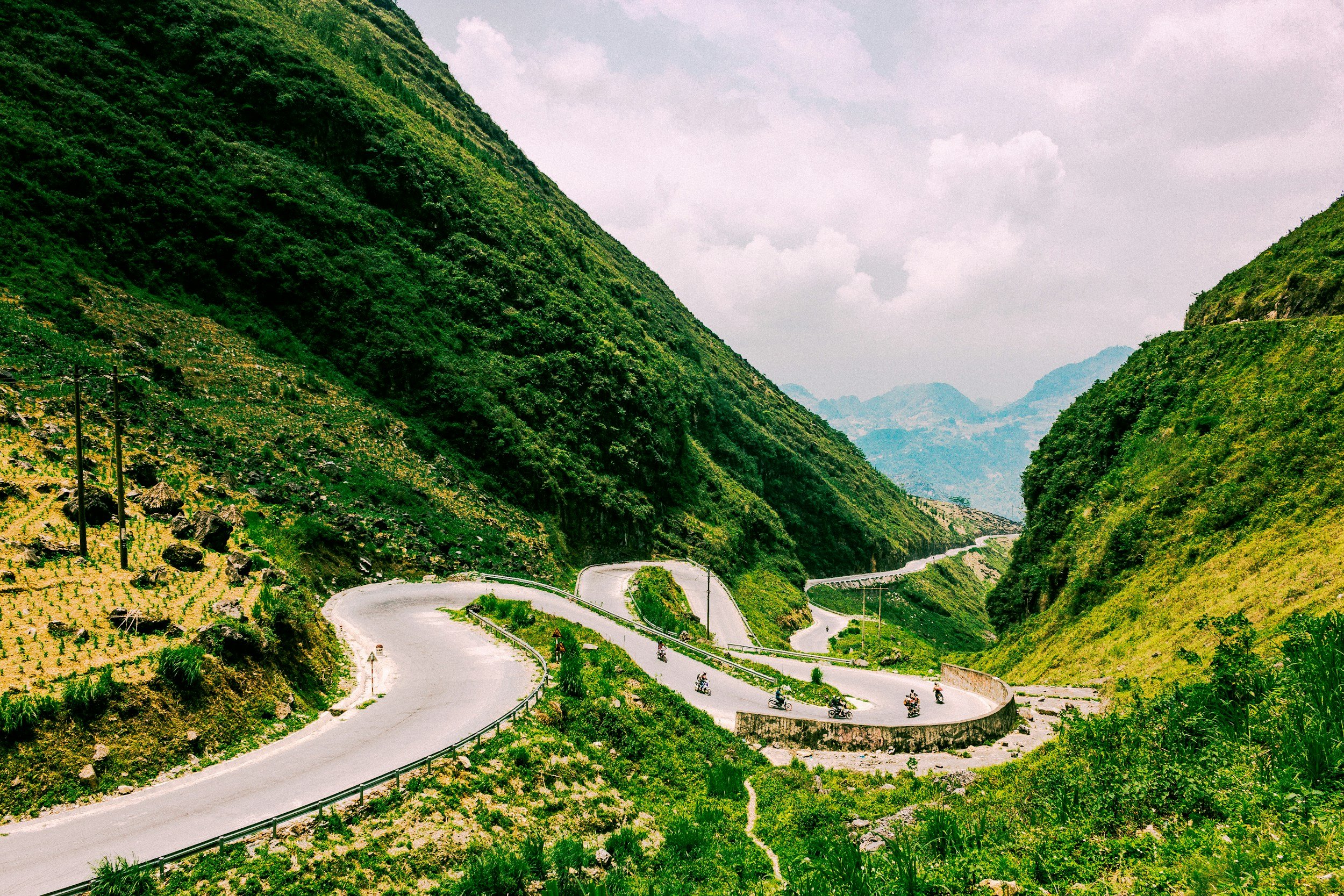 A winding mountain road with sharp curves, surrounded by lush green hills and vegetation.