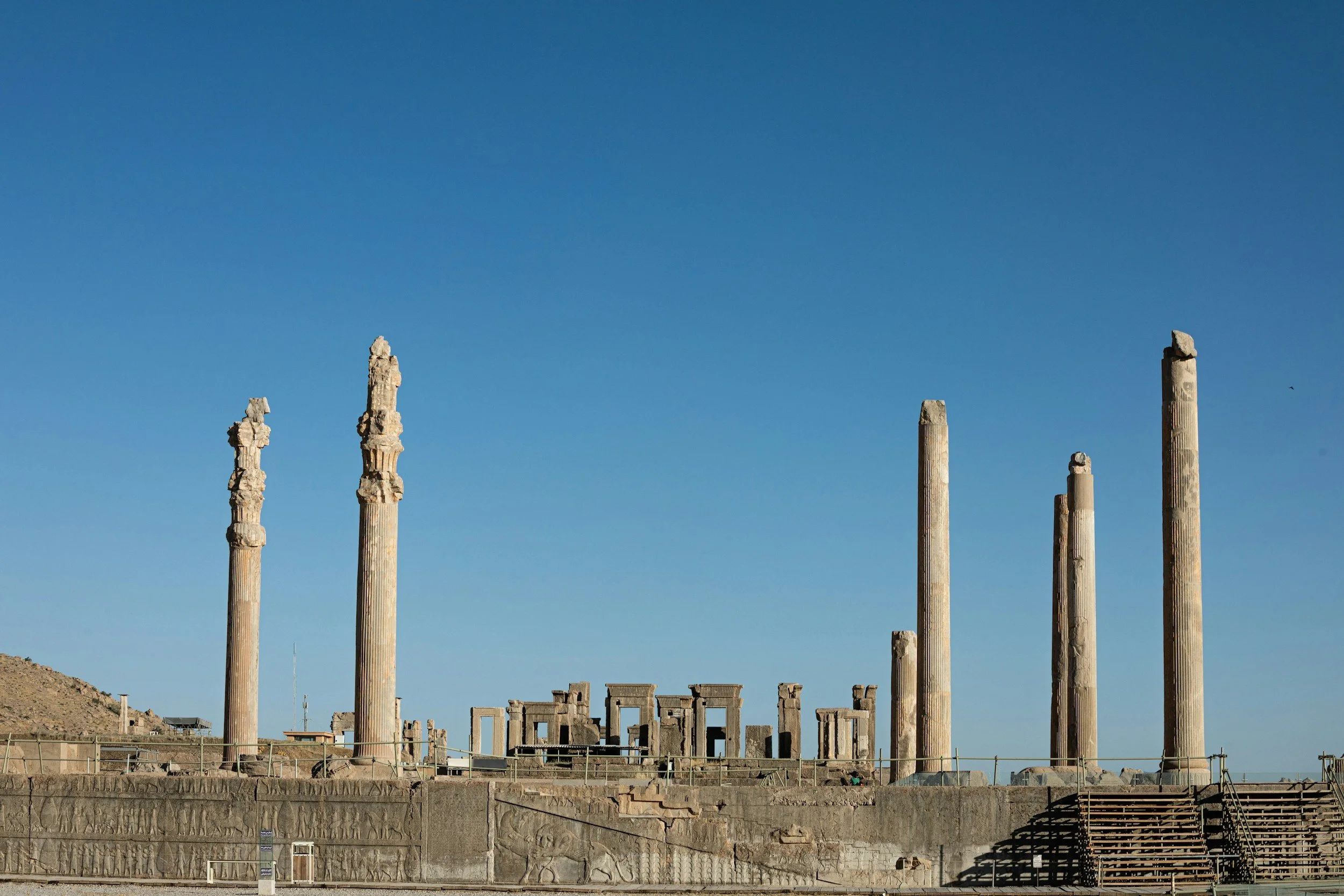 Ancient ruins of columns and structures at a historical site under a clear blue sky.