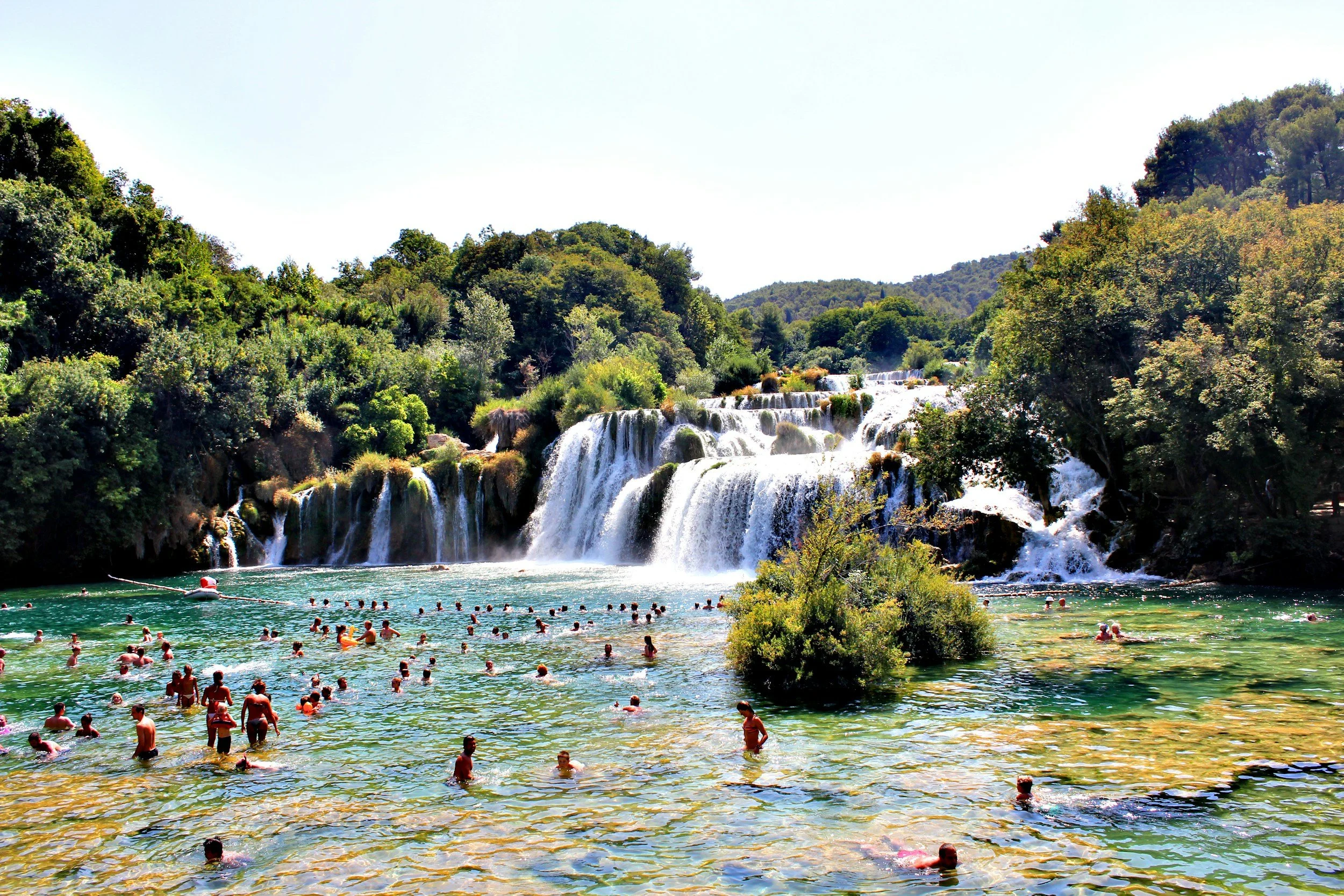 People swimming and enjoying the waterfall at Krka National Park in Croatia during daylight.