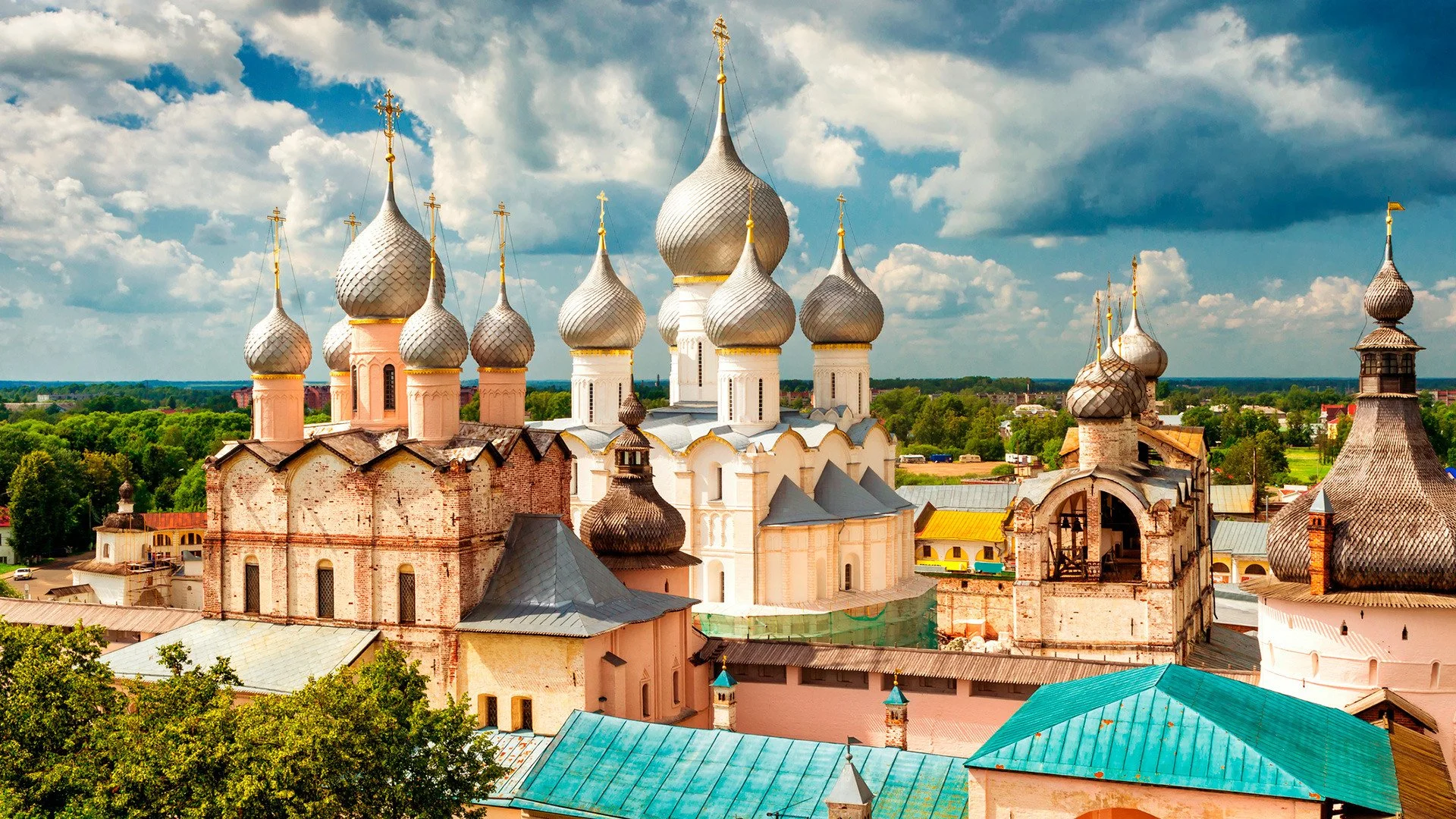 A church with onion-shaped domes in a Ukrainian village, surrounded by trees and a partly cloudy sky.
