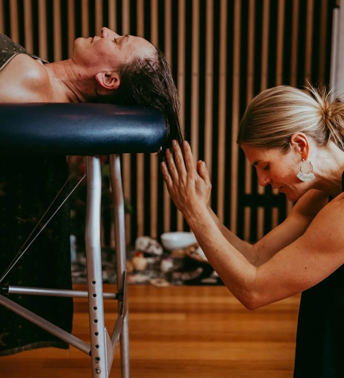 A woman receiving a Reiki healing session from another woman in a wellness center with a wooden interior.