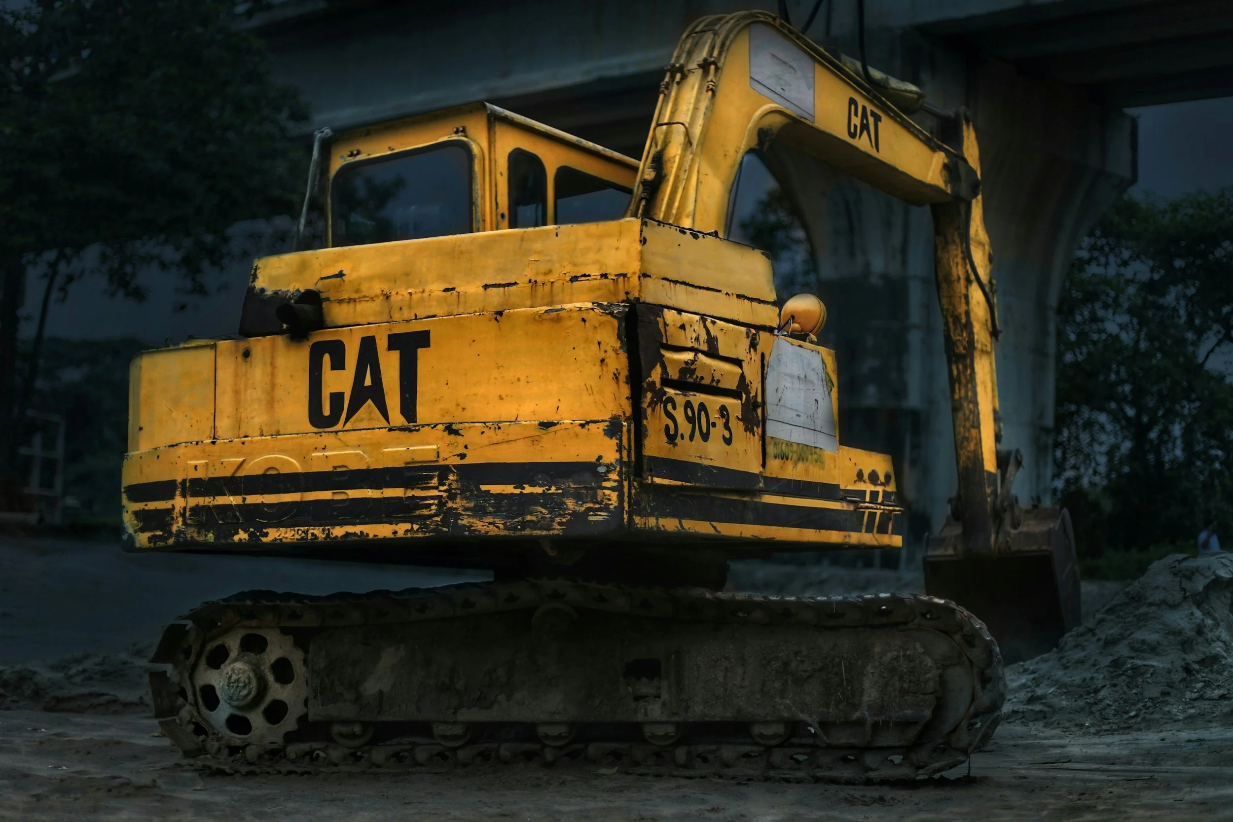 A yellow construction excavator with the brand name 'CAT' printed on it, positioned outdoors at a construction site.