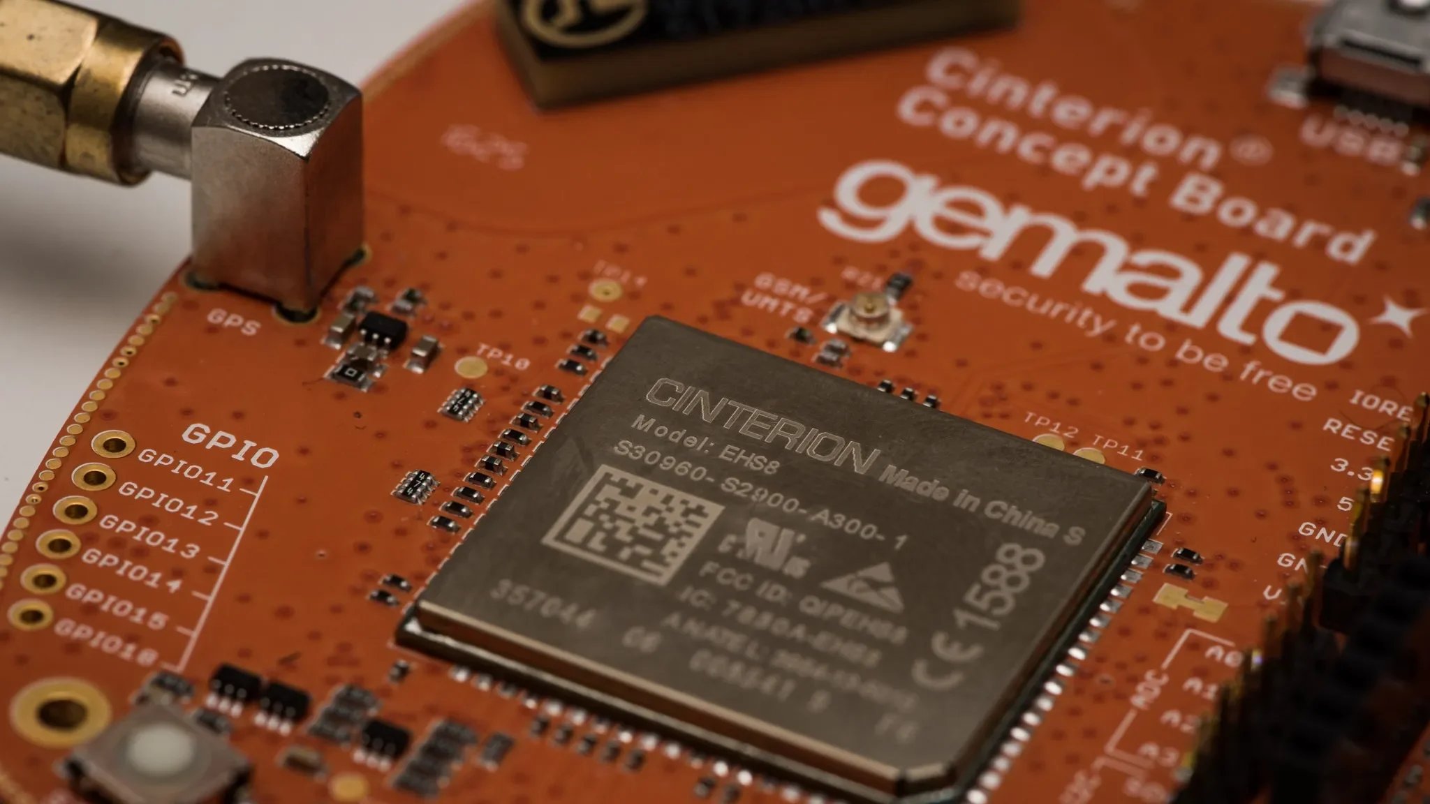 Close-up of an orange Banana Pi computer board with a CINTERION module, various small electronic components, and labels for GPIO pins.