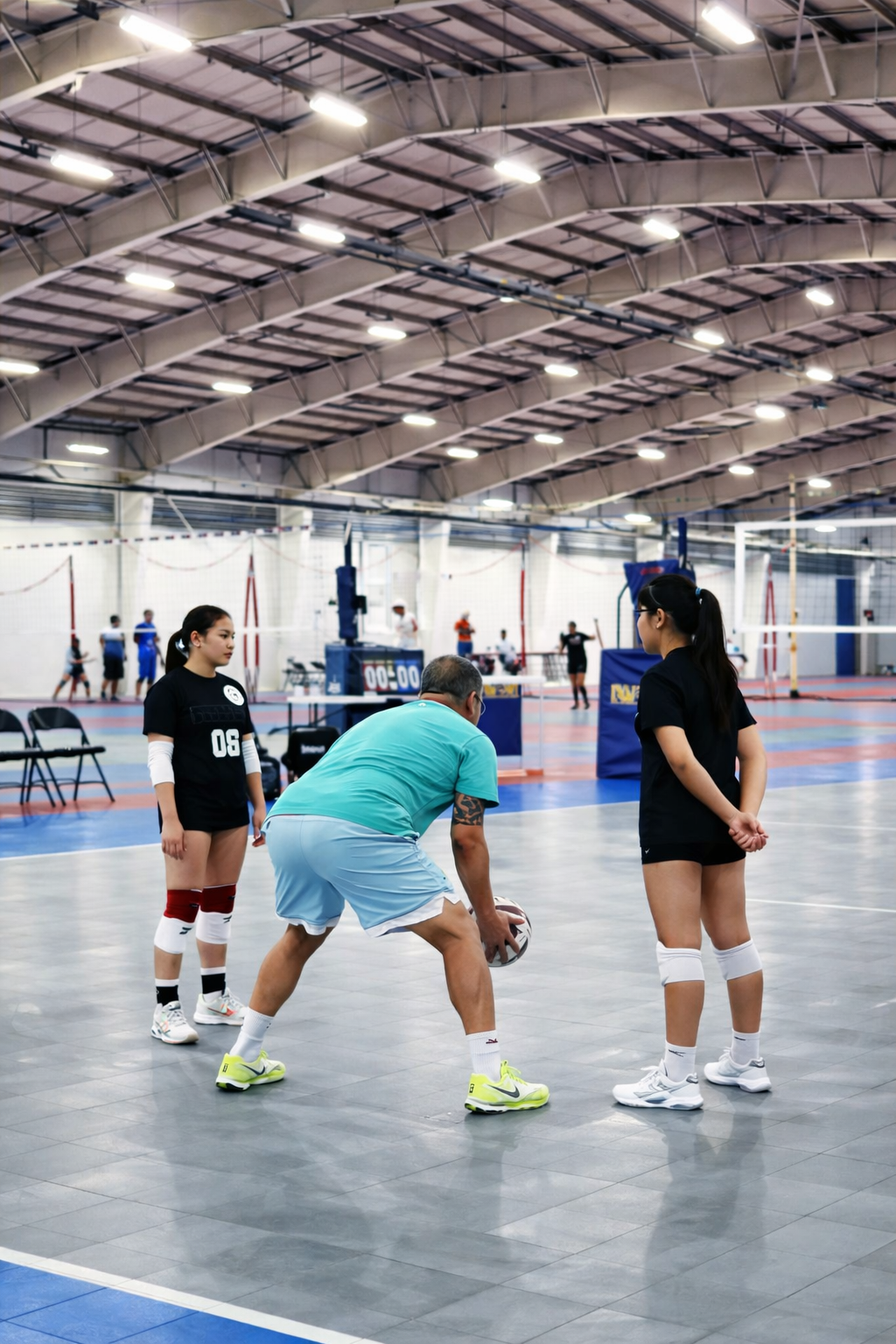 Coach demonstrating a ball-control drill with athletes during indoor volleyball training.