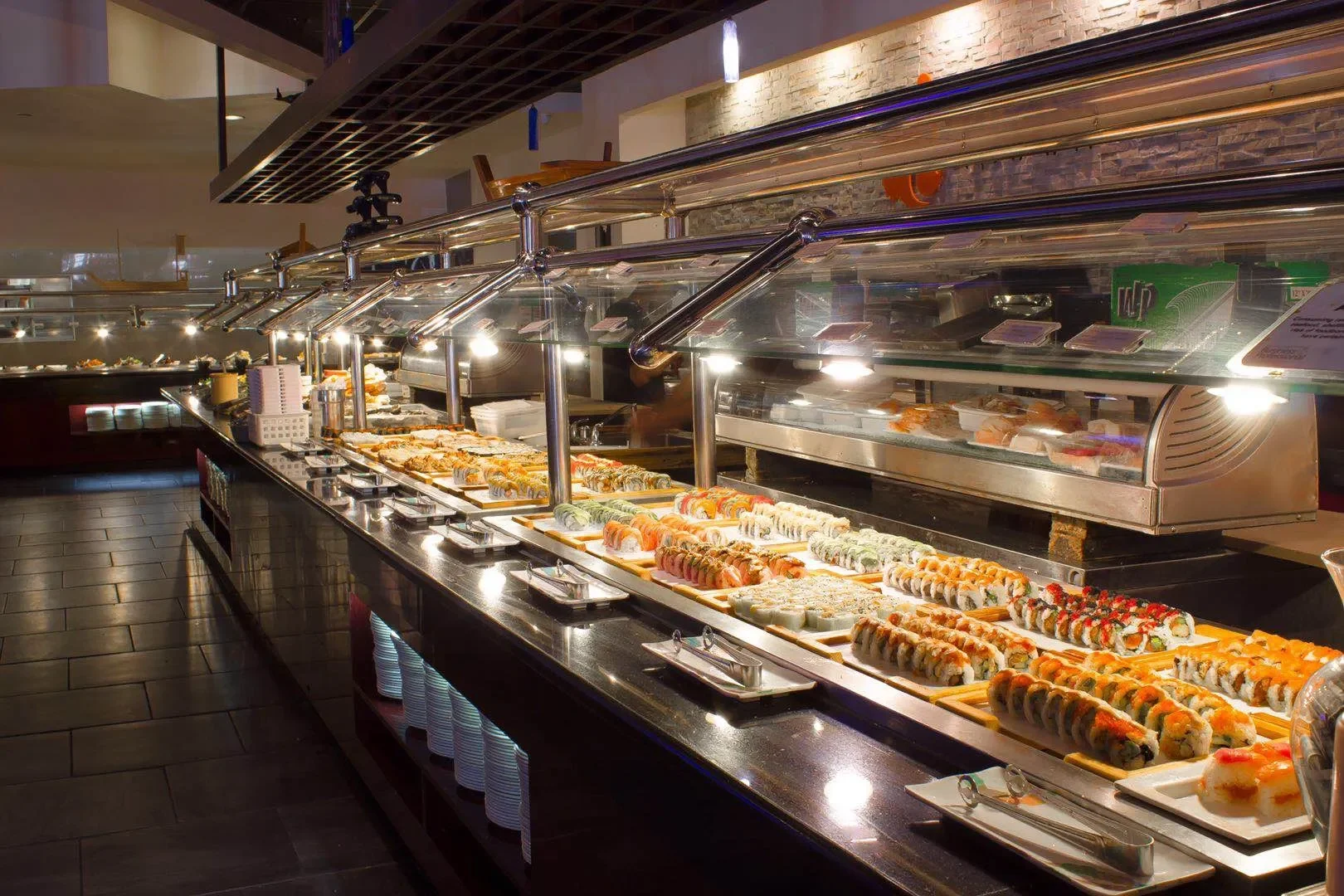 Sushi display case with various sushi rolls at a restaurant buffet.
