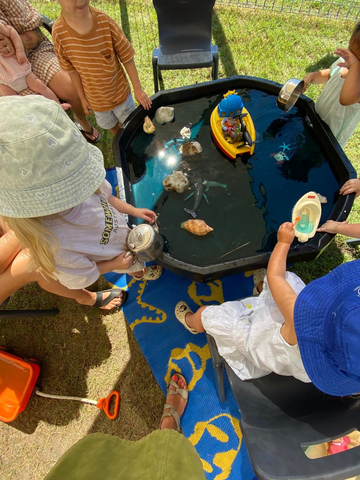 Children exploring water play together during an outdoor playgroup session.
