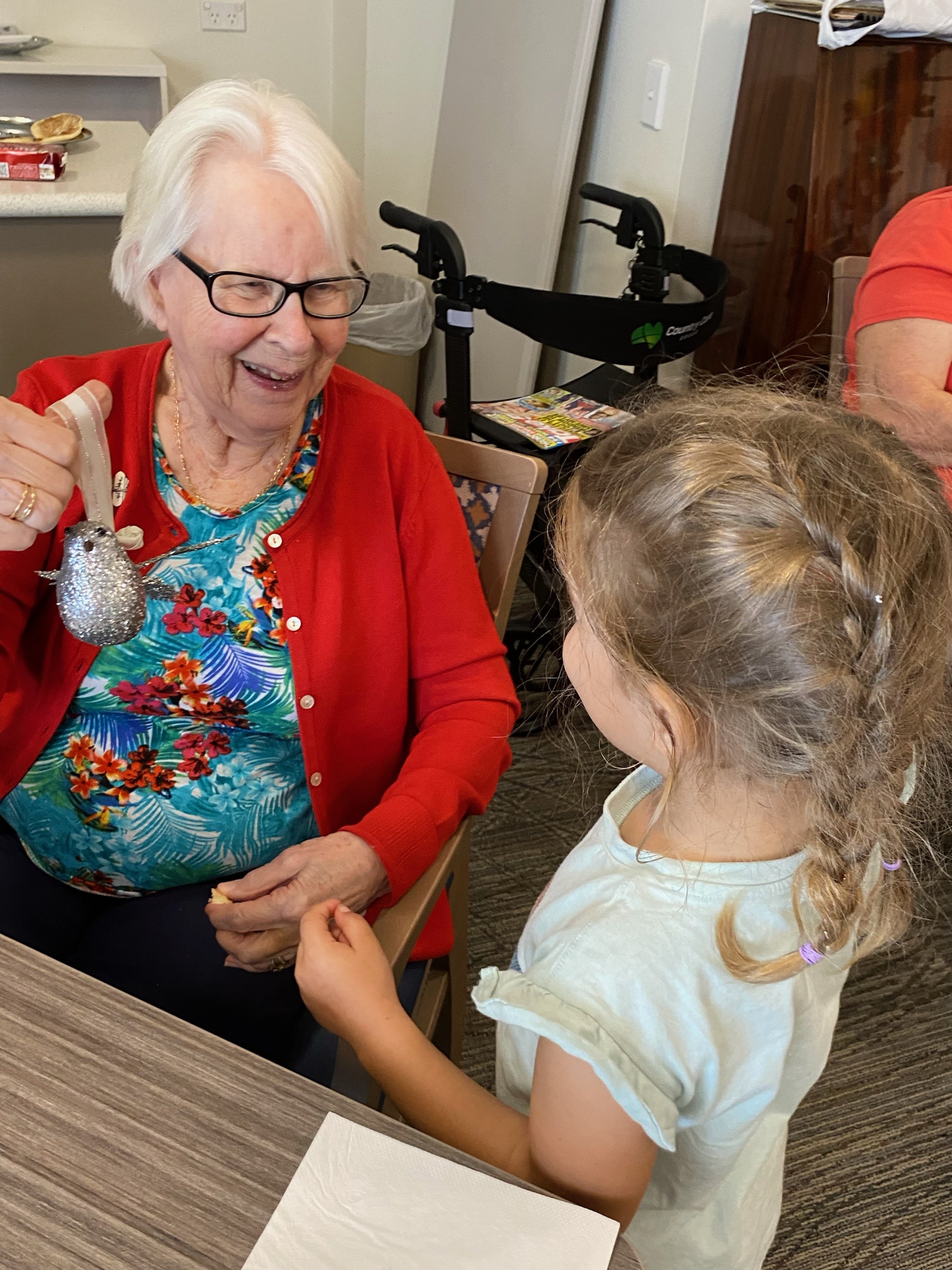 A preschool child and an older community member sharing a joyful conversation during a Grandfriends session.