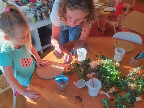 Educator and child exploring nature materials during a hands-on learning activity in the Whales room