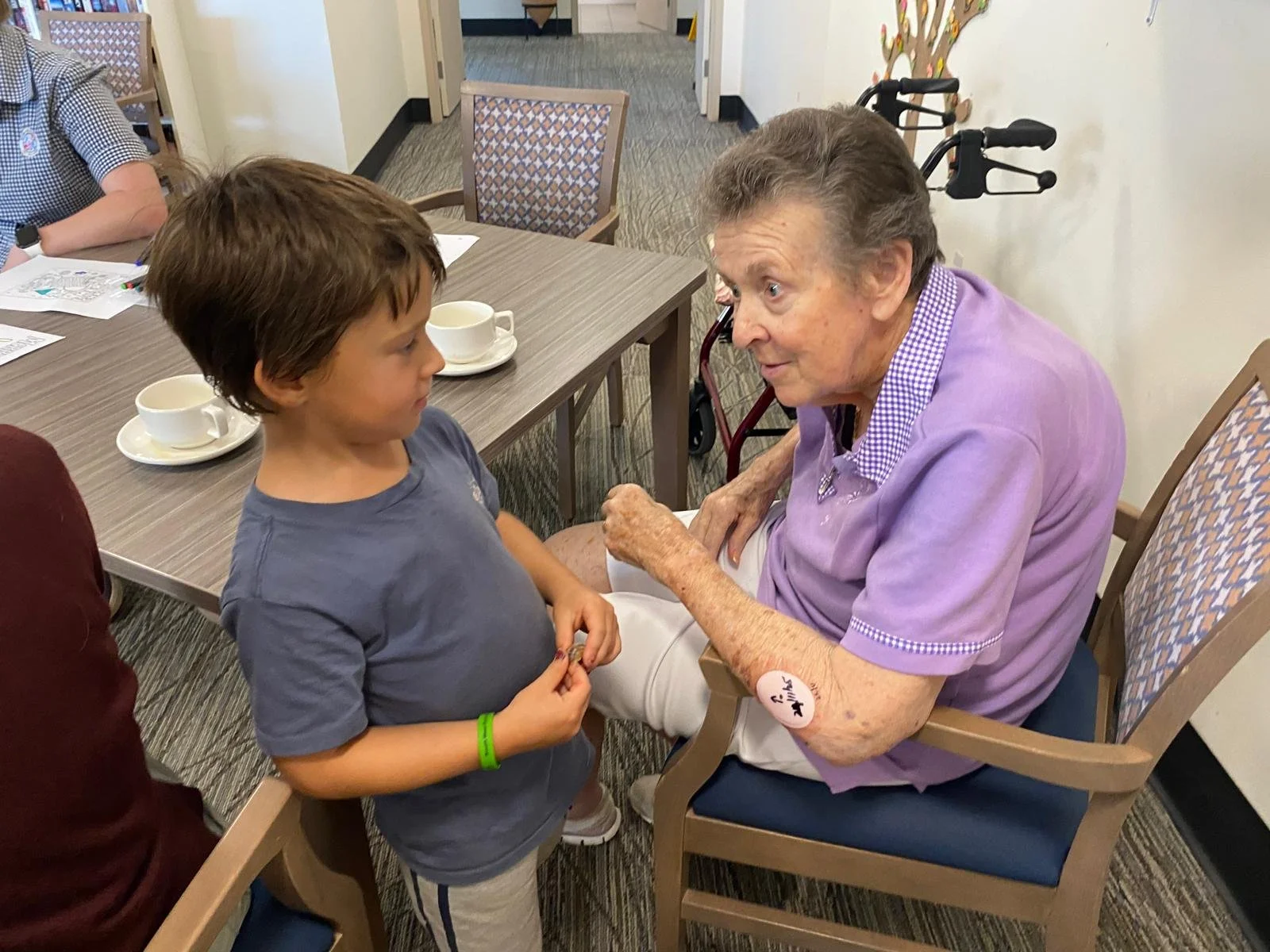 A preschool child chatting with an older community member during a Grandfriends visit.