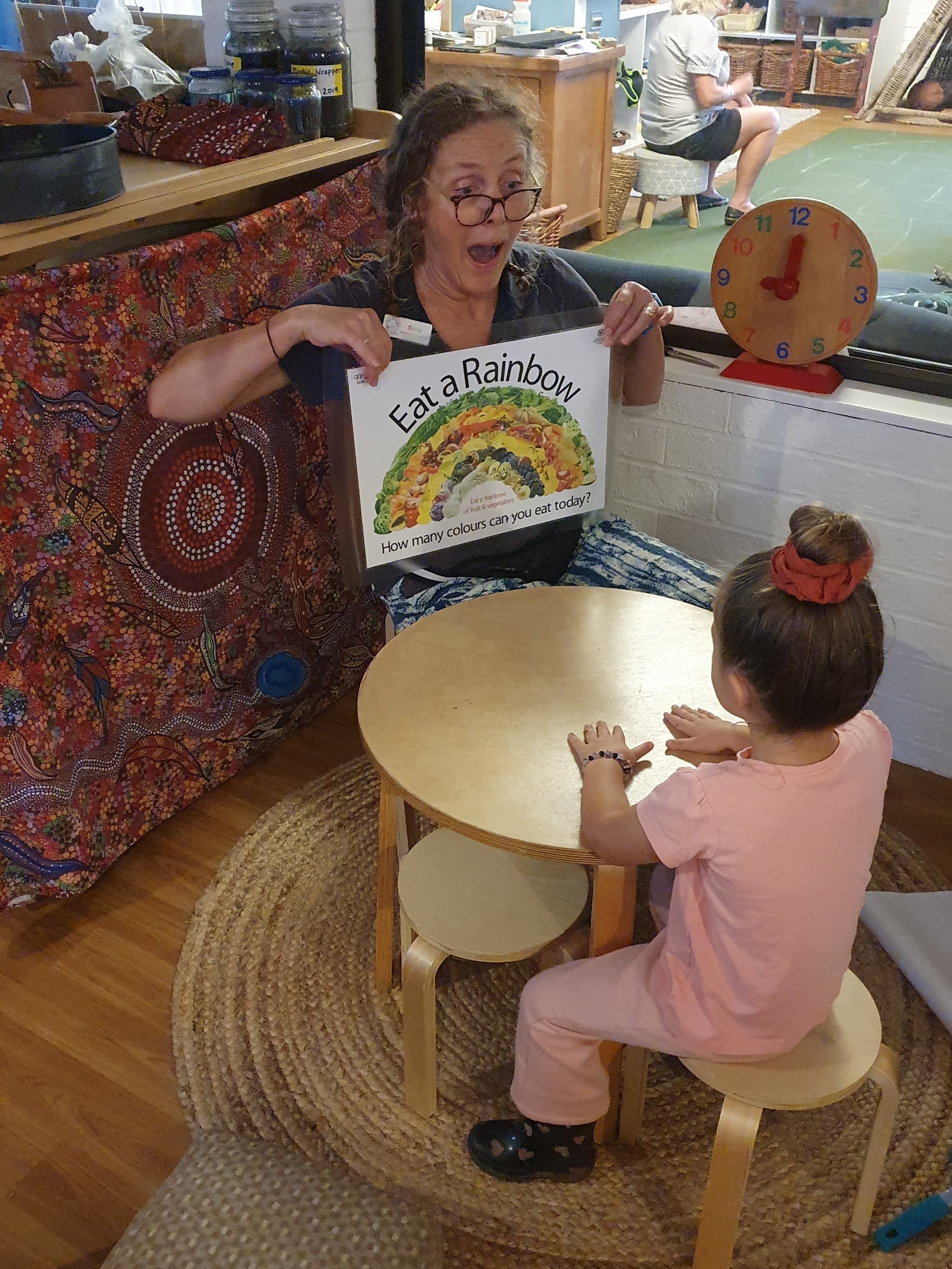 Educator reading with a child during a learning activity at South West Rocks Preschool.