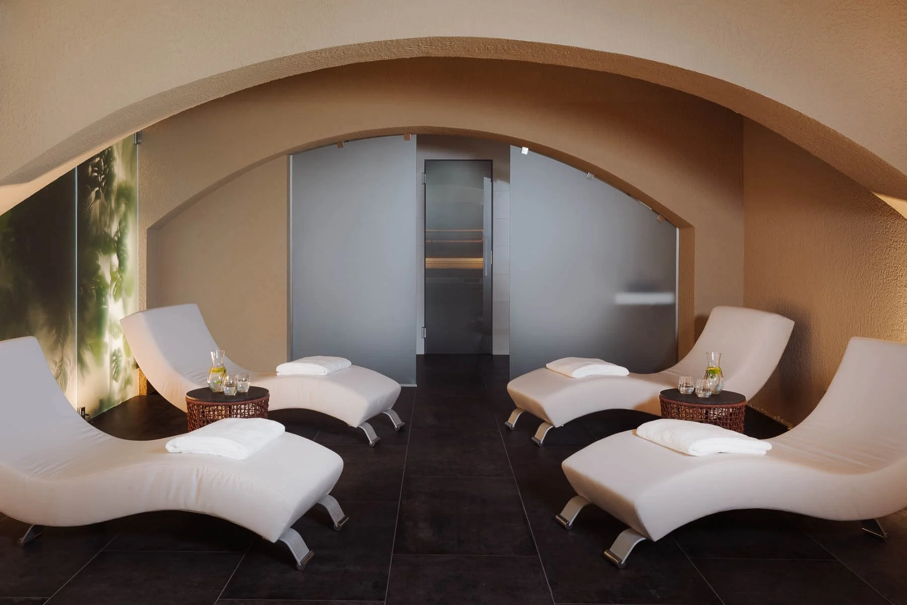 Architektonická fotografie wellness centra: detail klenutých stropů, náladového osvětlení a designových relaxačních lehátek.