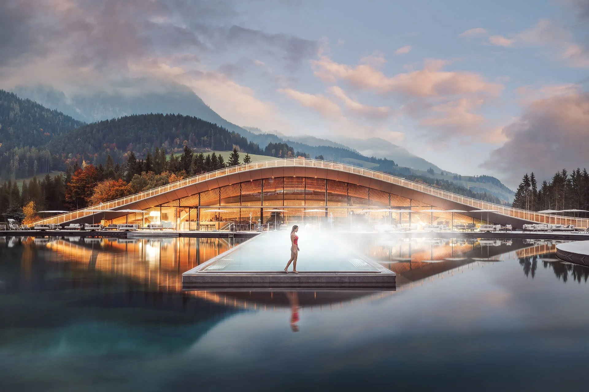 Hotel Krallerhof | Leogang, Austria: Wellness pavilon Atmosphere s organickou dřevěnou architekturou odrážející se na hladině jezera při soumraku.
