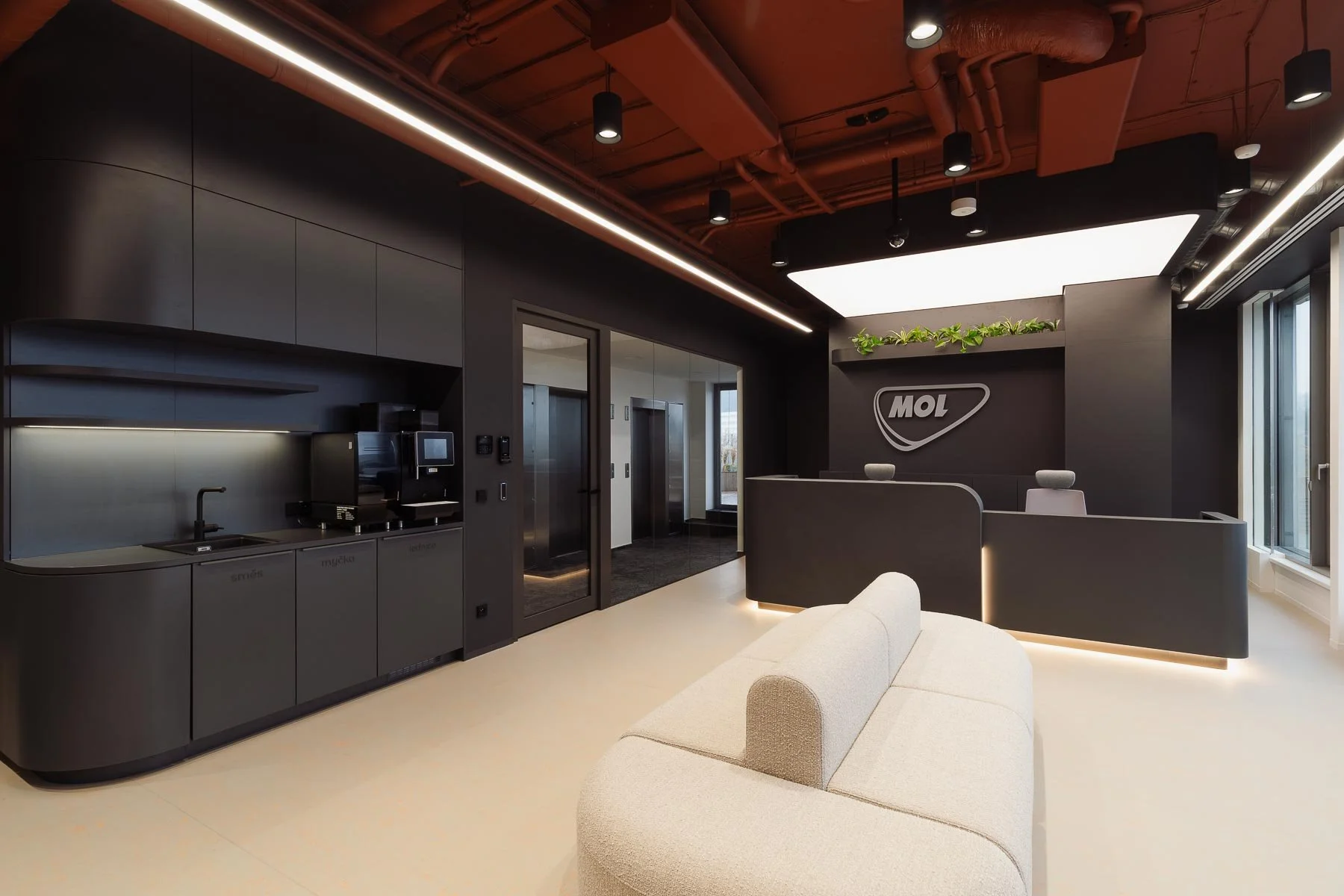 Moderní kancelářské prostory s minimalistickou recepcí, logem MOL a designovou kuchyňkou.