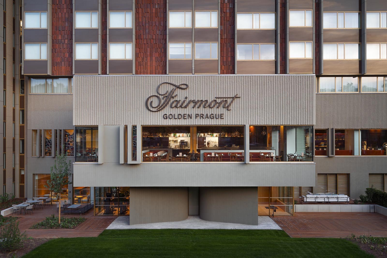 Architektonická fotografie fasády hotelu Fairmont Golden Prague. Moderní exteriérový design s velkoformátovým prosklením a venkovní hotelovou terasou v Praze.