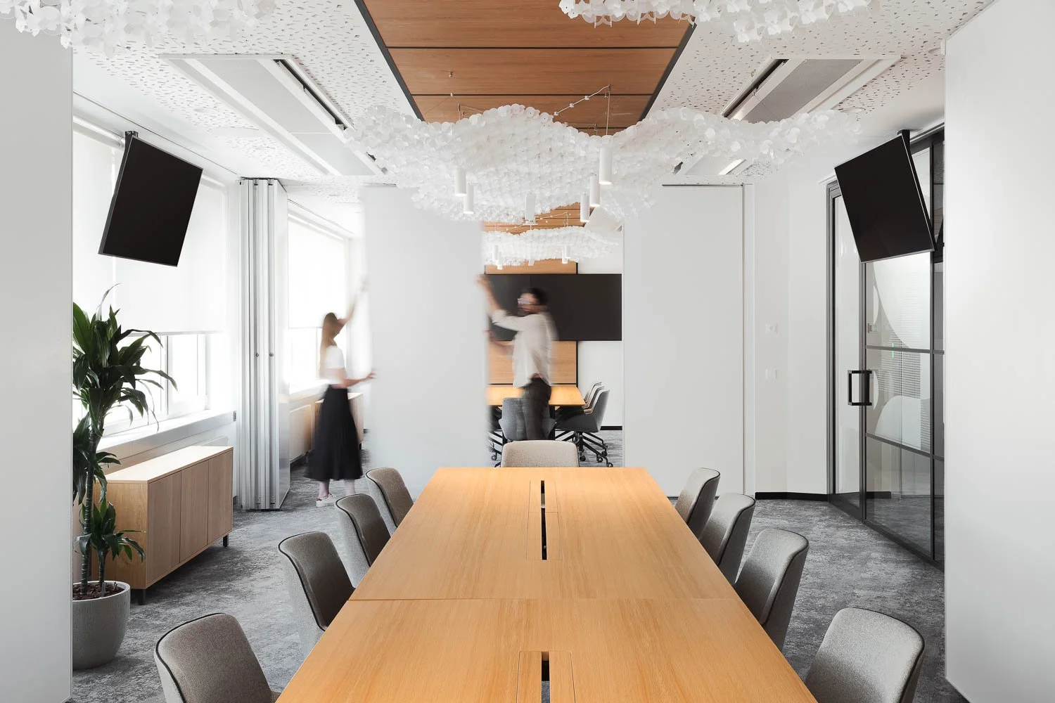 Moderní zasedací místnost s dlouhým masivním stolem, prosklenými příčkami a unikátní bílou instalací stropního podhledu v Praze.