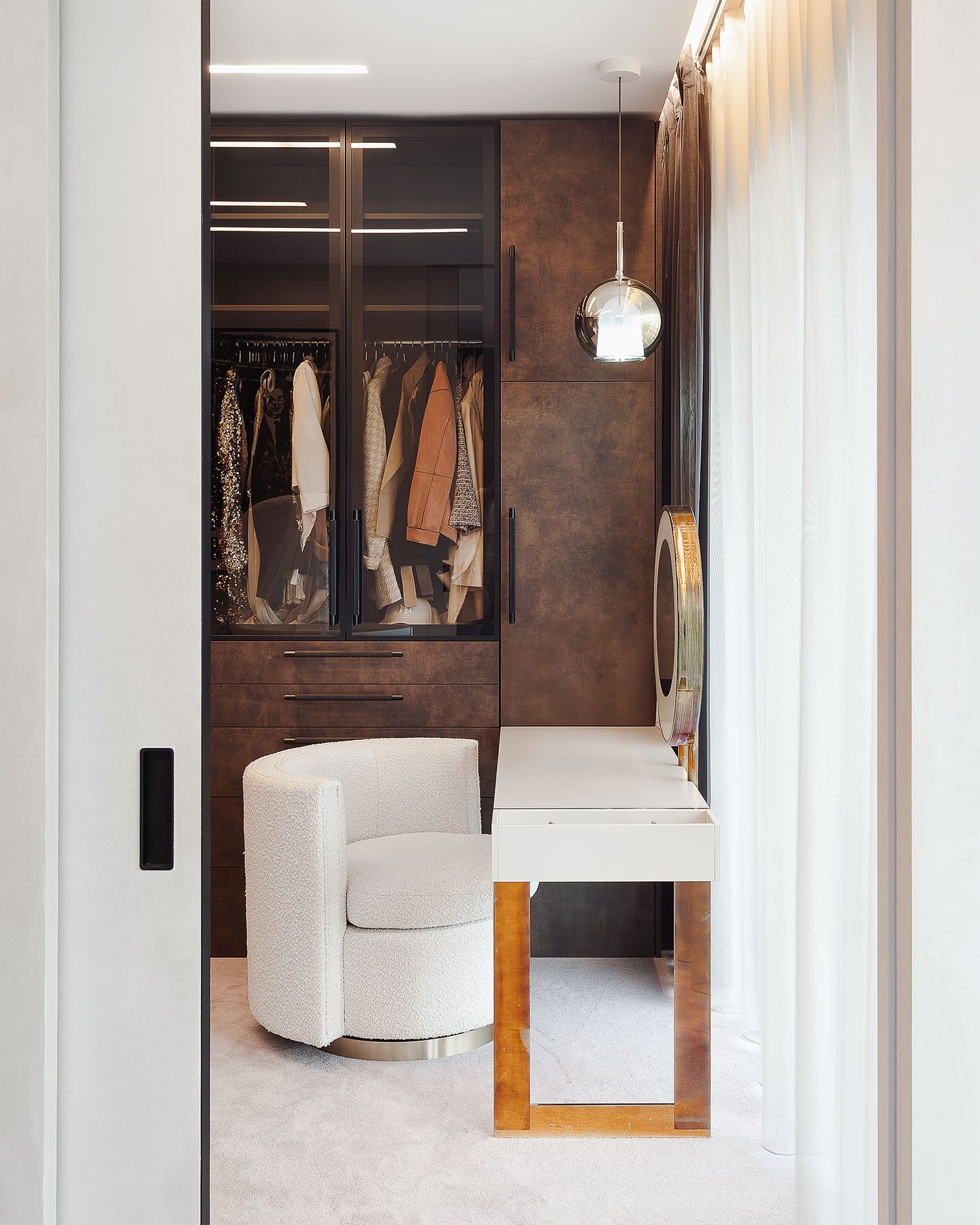 Luxusní interiér šatny s podsvíceným zrcadlem, kosmetickým stolkem a designovým křeslem.