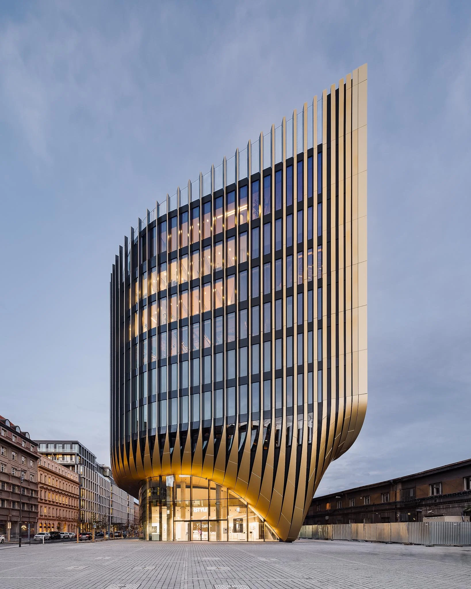 Architektonická fotografie: budova Masaryčka v Praze od Zaha Hadid Architects s ikonickou zlatou fasádou a lamelami.