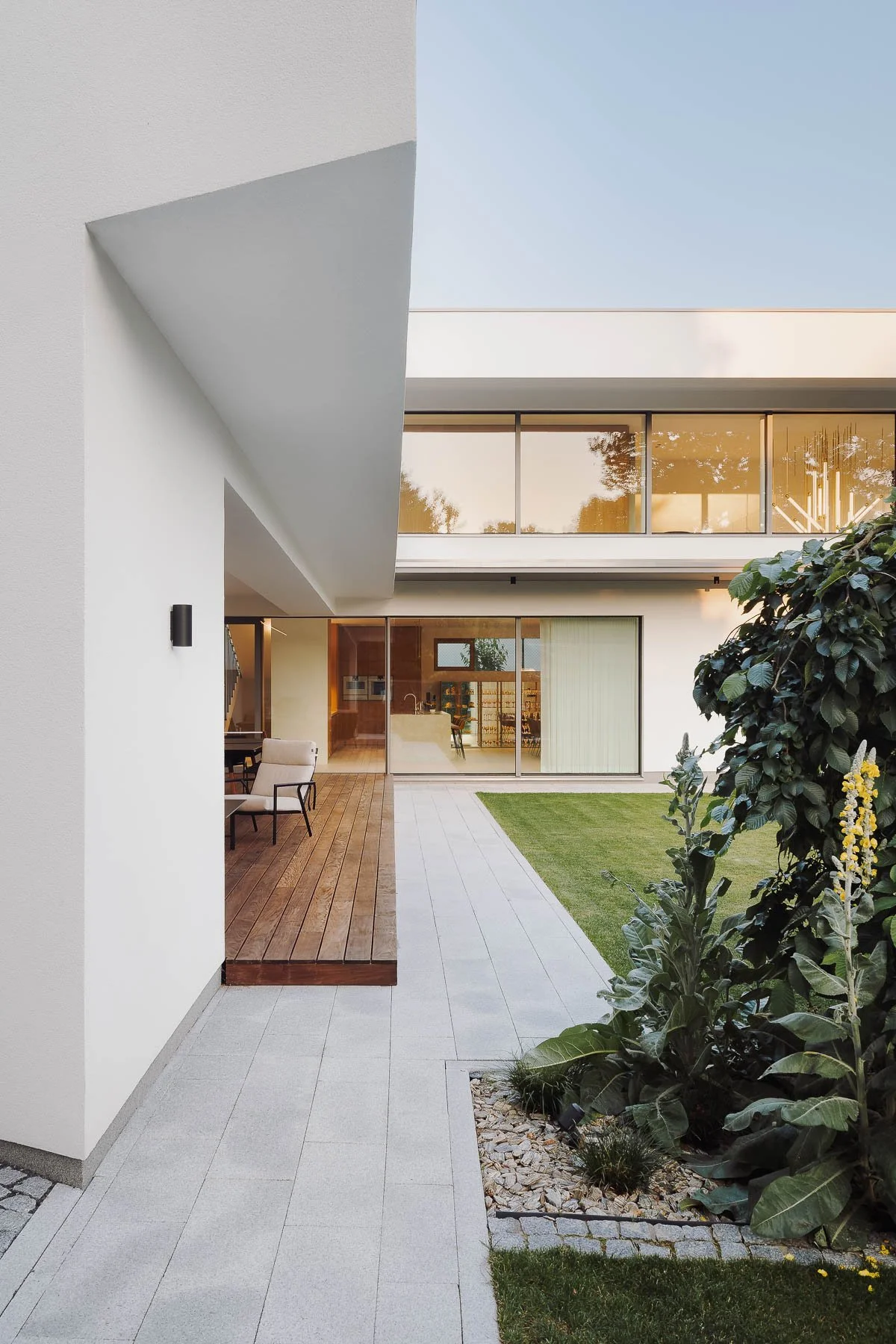 Záběr na architekturu moderního domu s terasou a průhledem do interiéru.