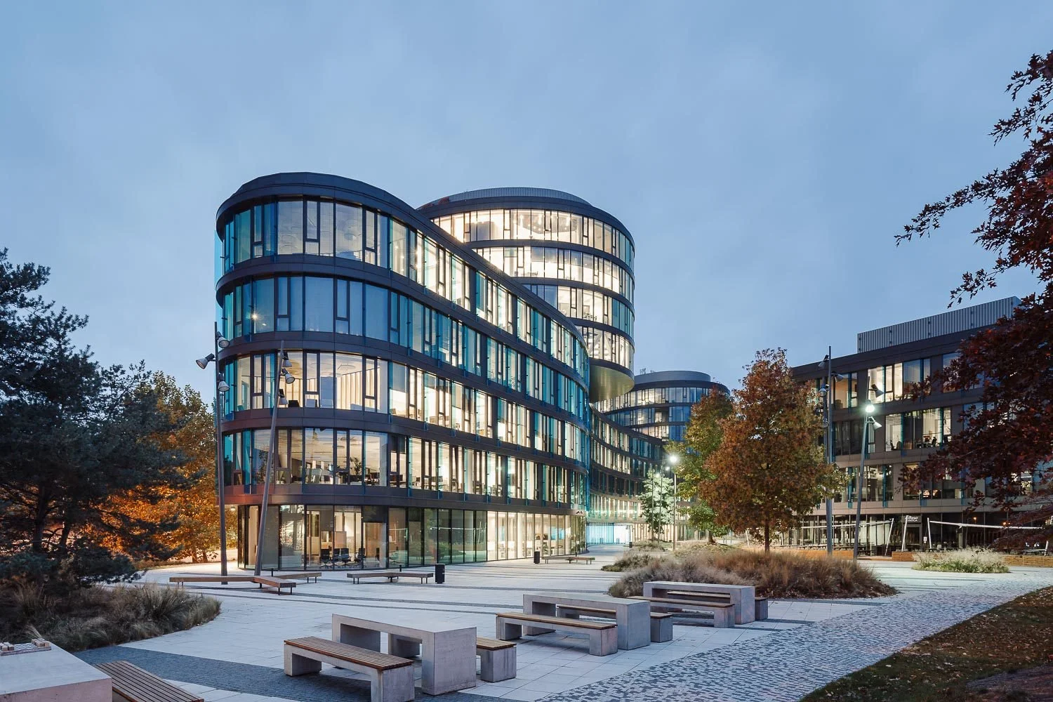 Administrativní komplex Waltrovka: večerní pohled na moderní prosklenou architekturu a nasvícené veřejné prostranství v Praze.