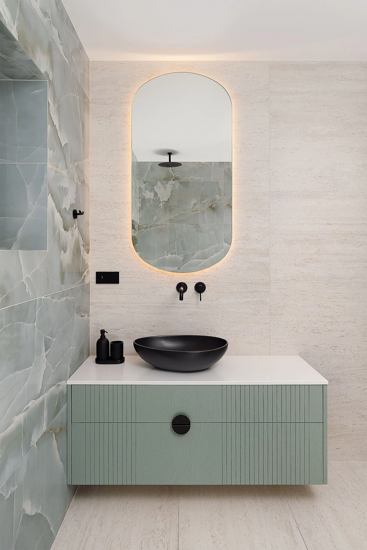 Detailní fotografie interiéru koupelny s kamenným obkladem a designovým umyvadlem.