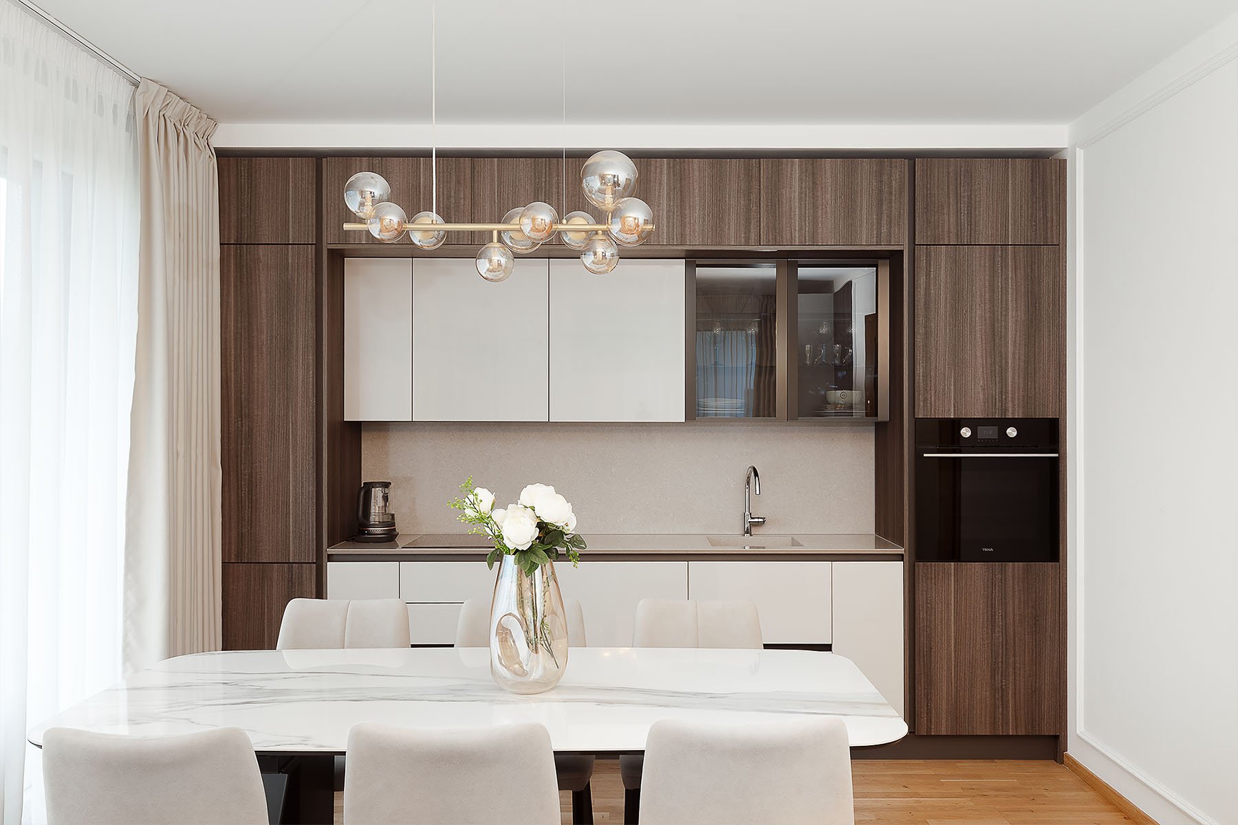 Moderní kuchyně s dřevěným dekorem a mramorovým stolem.