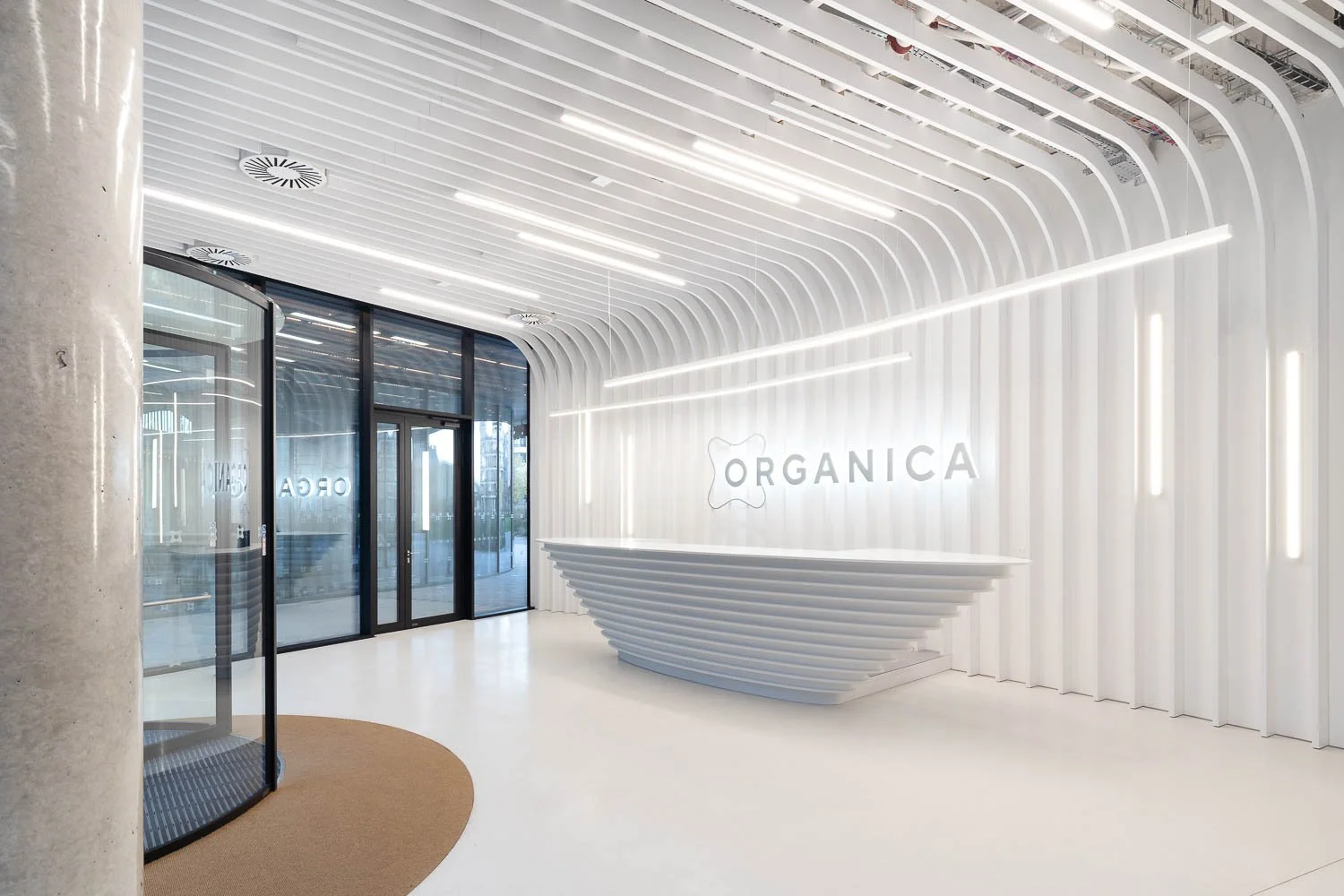 Moderní designové lobby budovy Organica s bílými žebrovanými stěnami a elegantním pultem.