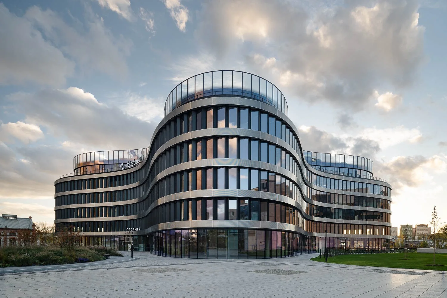 Administrativní budova Organica se zaoblenou prosklenou fasádou, horizontálními liniemi a organickou architekturou v Ostravě.