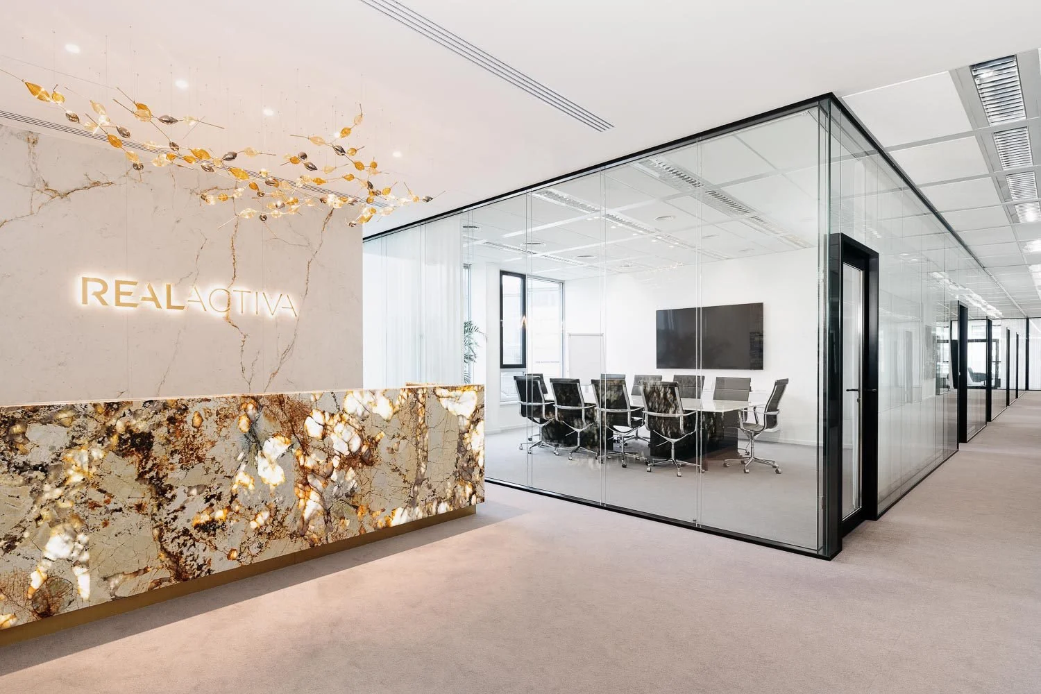 Moderní kancelářská recepce s mramorovým stolem, prosklená zasedací místnost.