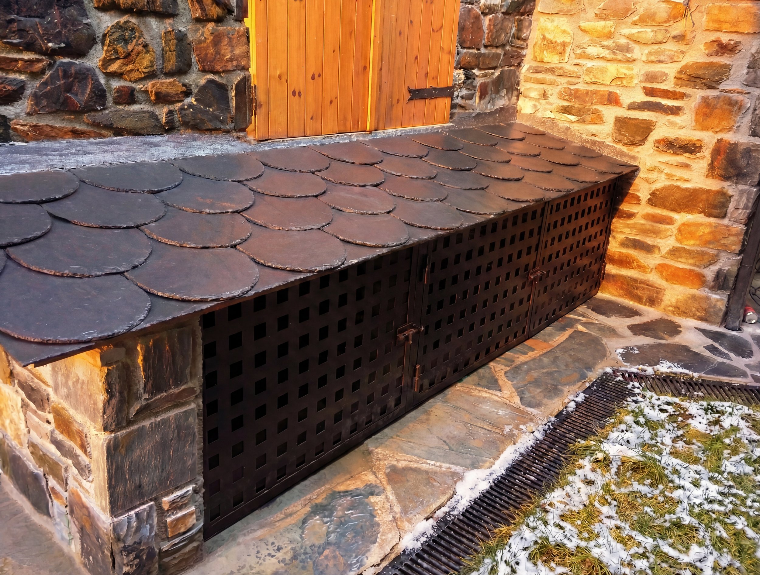 Armario a medida con acabado de piedra y pizarra en entrada de refugio de montaña en La Cerdanya. Solución de logística alpina para almacenar material de esquí.