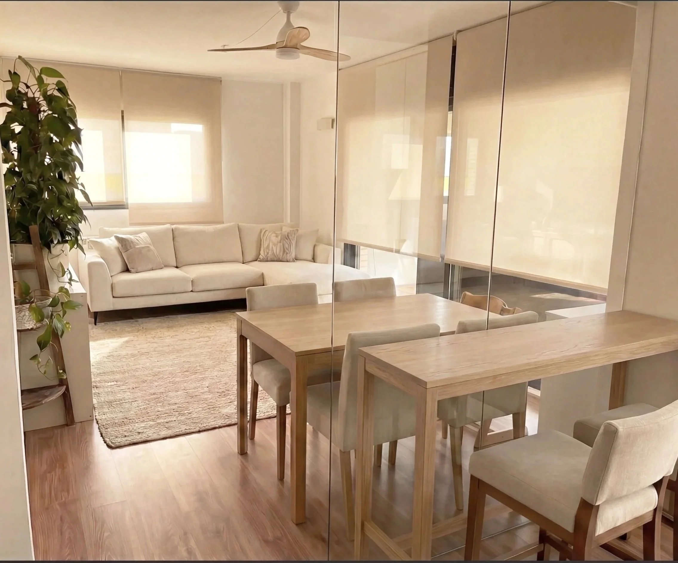 "Salón comedor con cerramiento de cristal y madera en interiorismo residencial en Sant Cugat. Espacio abierto que maximiza la luz natural en reforma de 74m²."