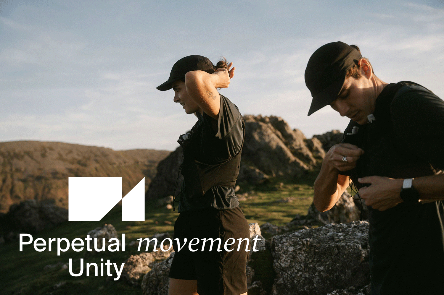 Deux personnes en tenue de sport, portant des casquettes noires, dans un paysage naturel avec des rochers et des collines, en train de se préparer à faire un exercice ou une activité pour la marque HOPAAL.