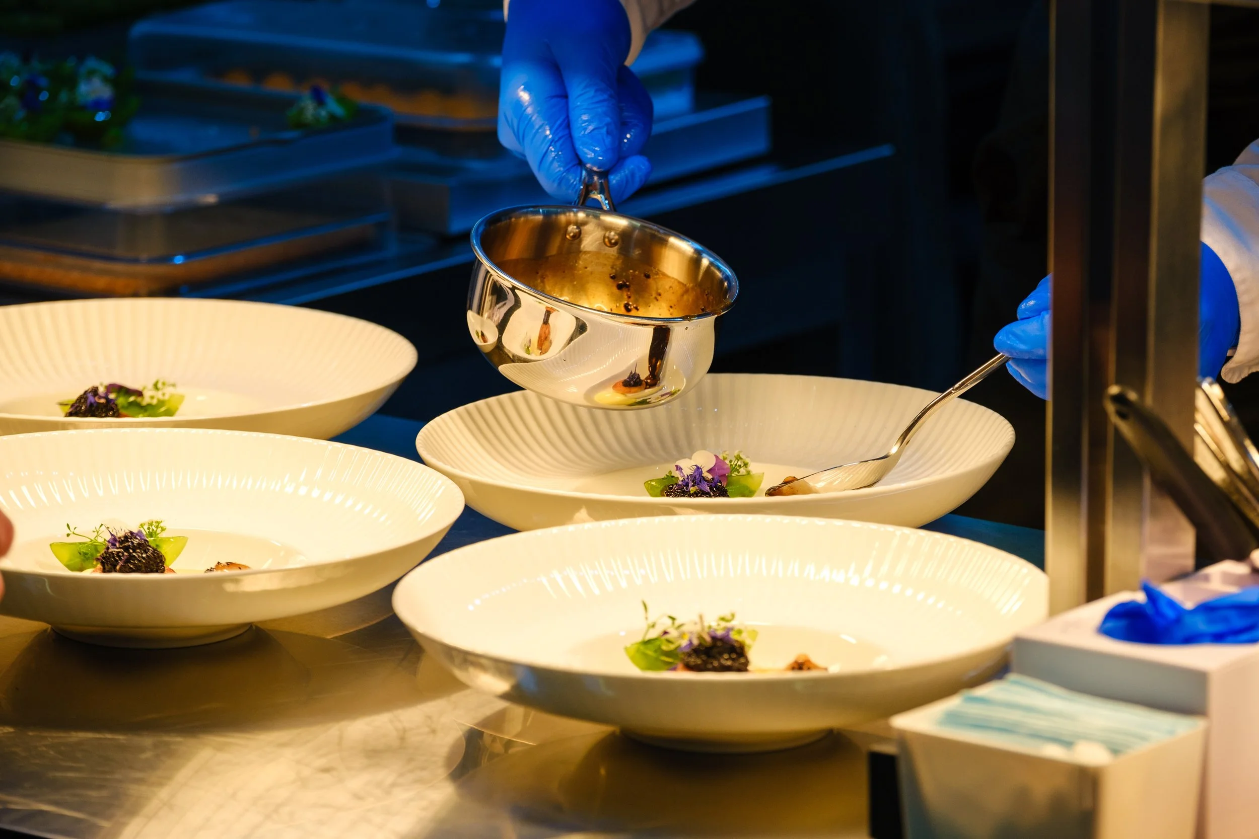 Kokk Andreas Fjellheim legger saus på tallerkener med mat under konkurransen IKA Culinary Olympics. 