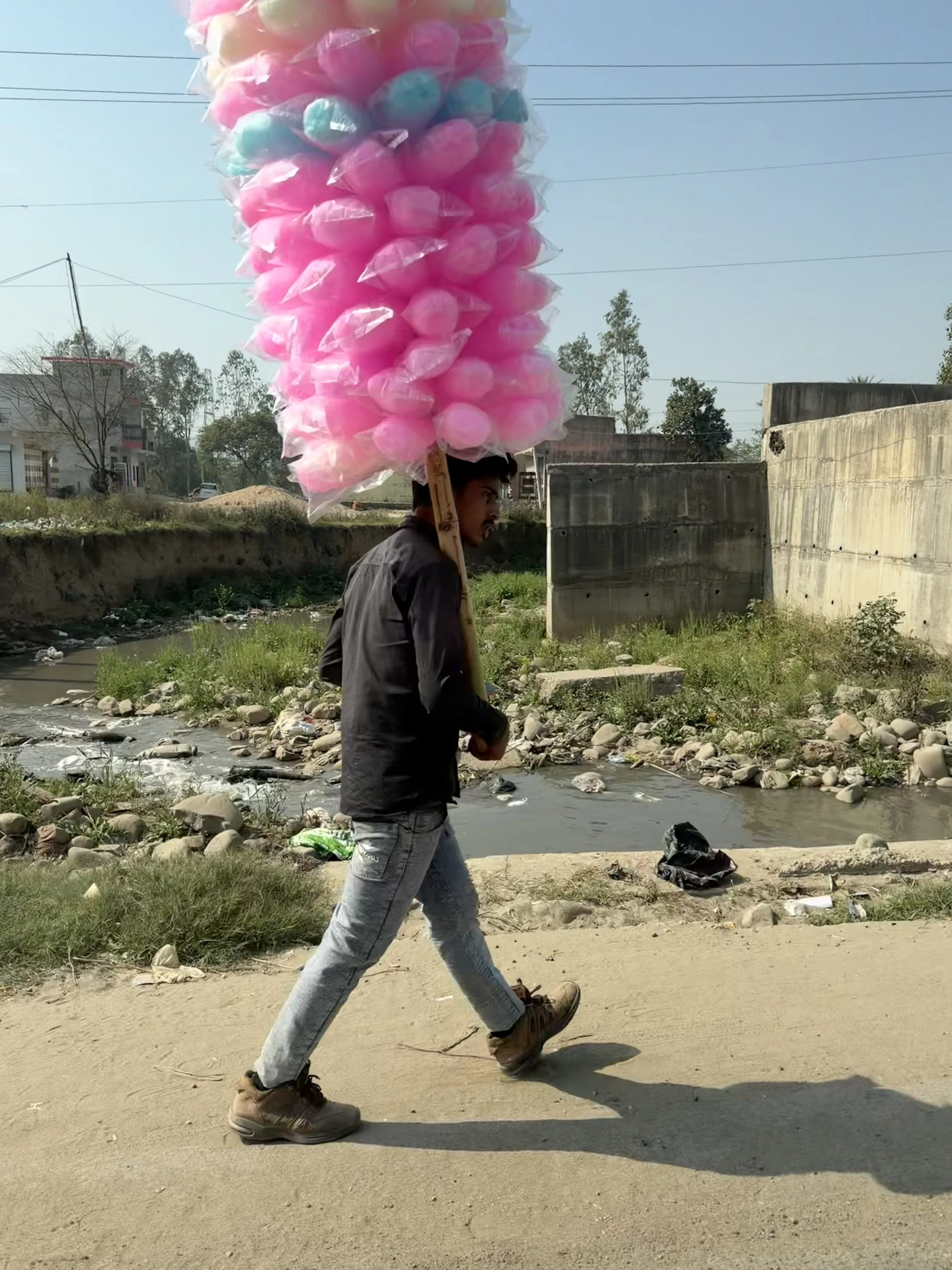 Man carrying bags of candy floss beside the road during our drive across Punjab to Amritsar