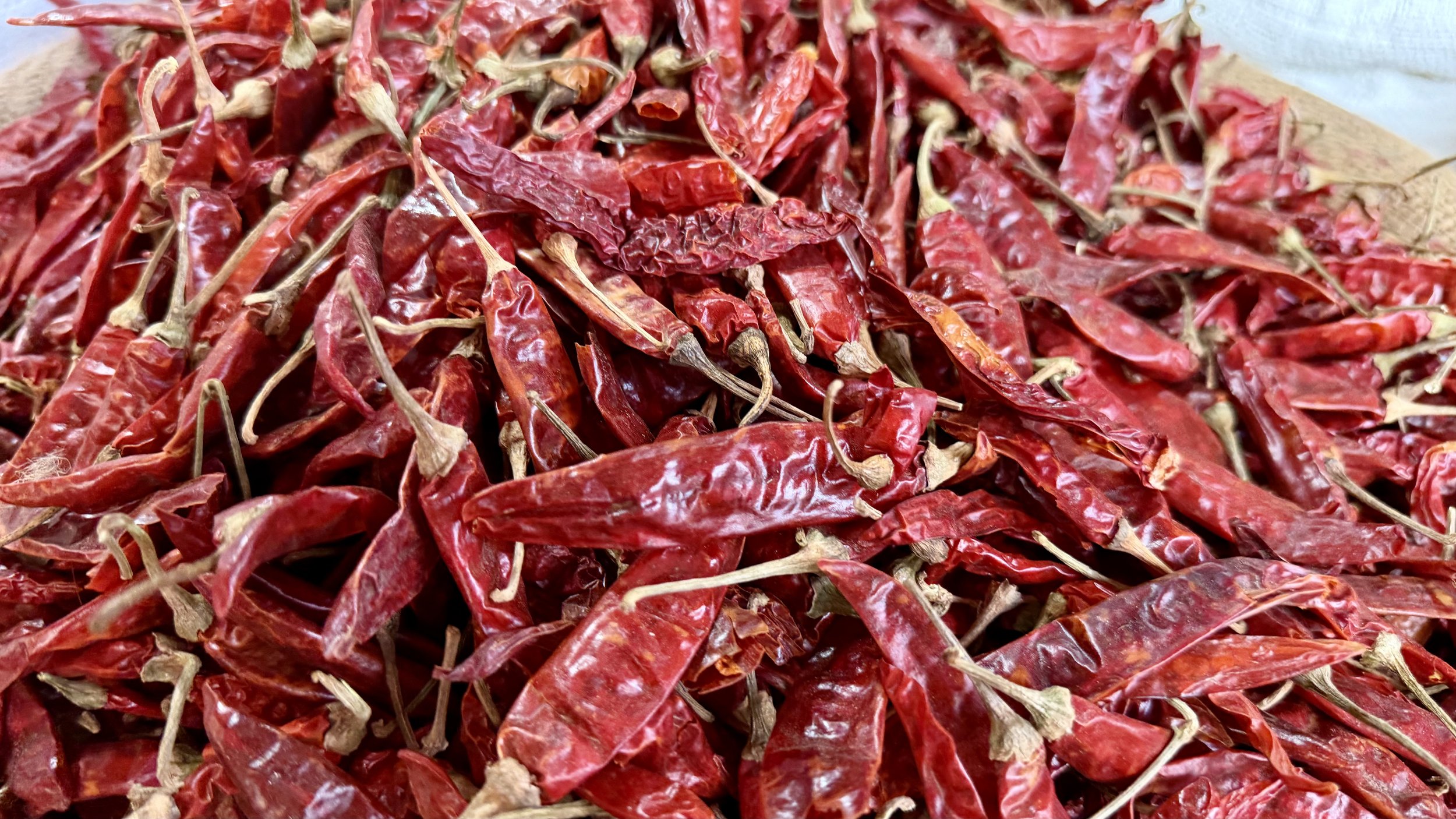Close-up of dried red chillies piled high in a market sack.