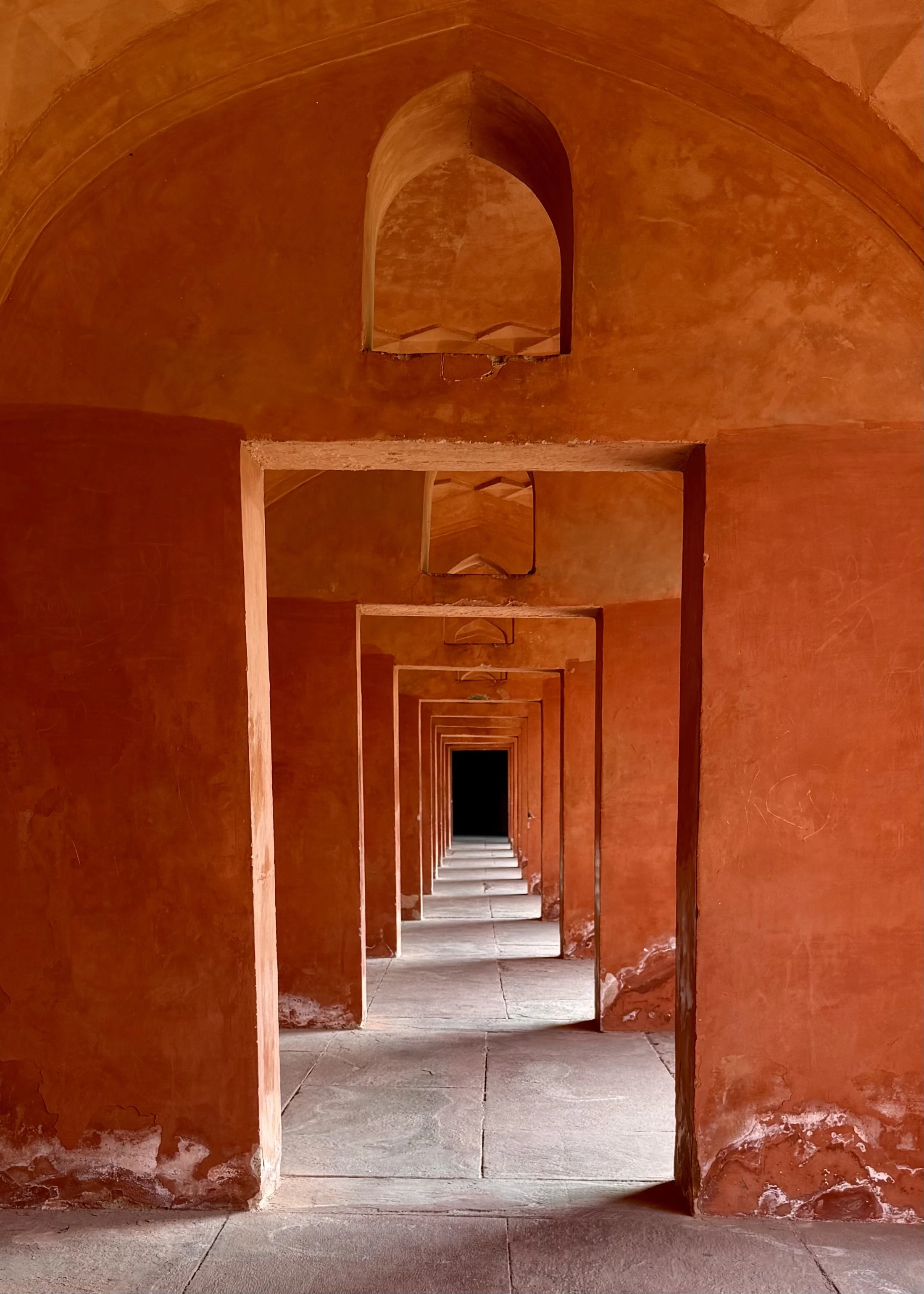 Series of arches in a red sandstone corridor at the Taj Mahal complex in Agra