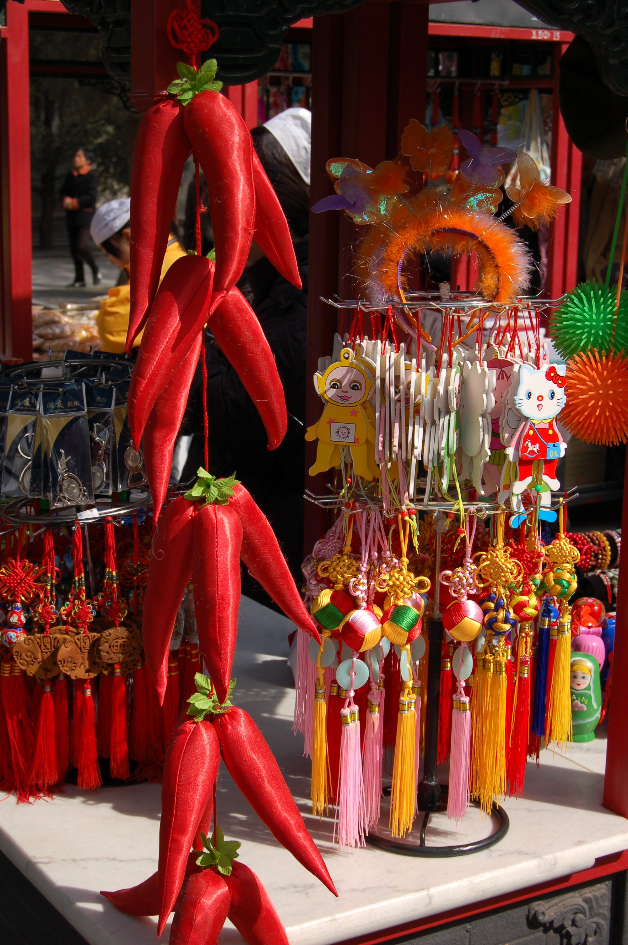 Souvenir stalls inside the Summer Palace grounds, with strings of red dried peppers and small decorative items hanging in sunlight.