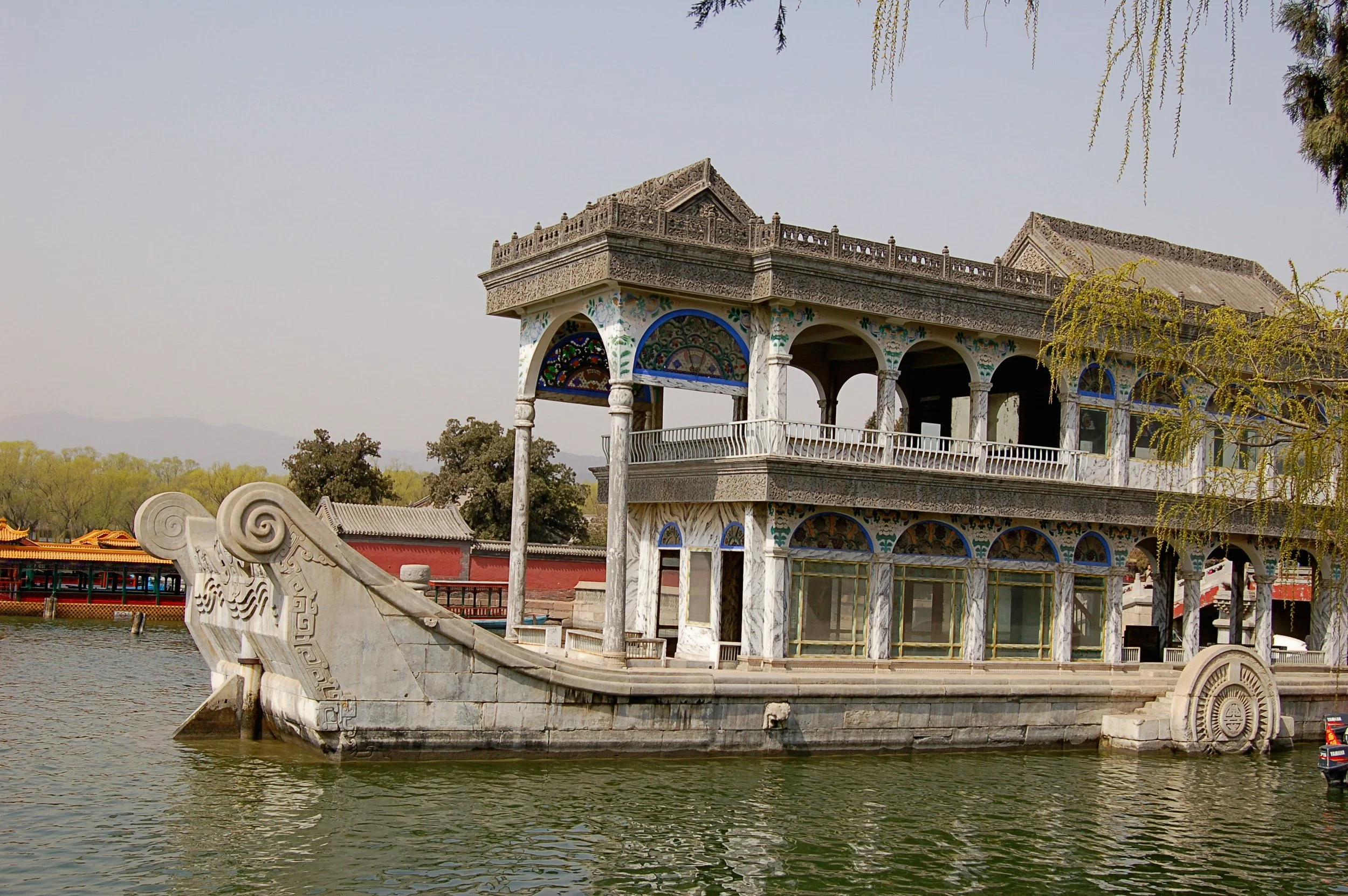The Marble Boat on Kunming Lake at the Summer Palace, viewed from the shore with calm water and surrounding trees.