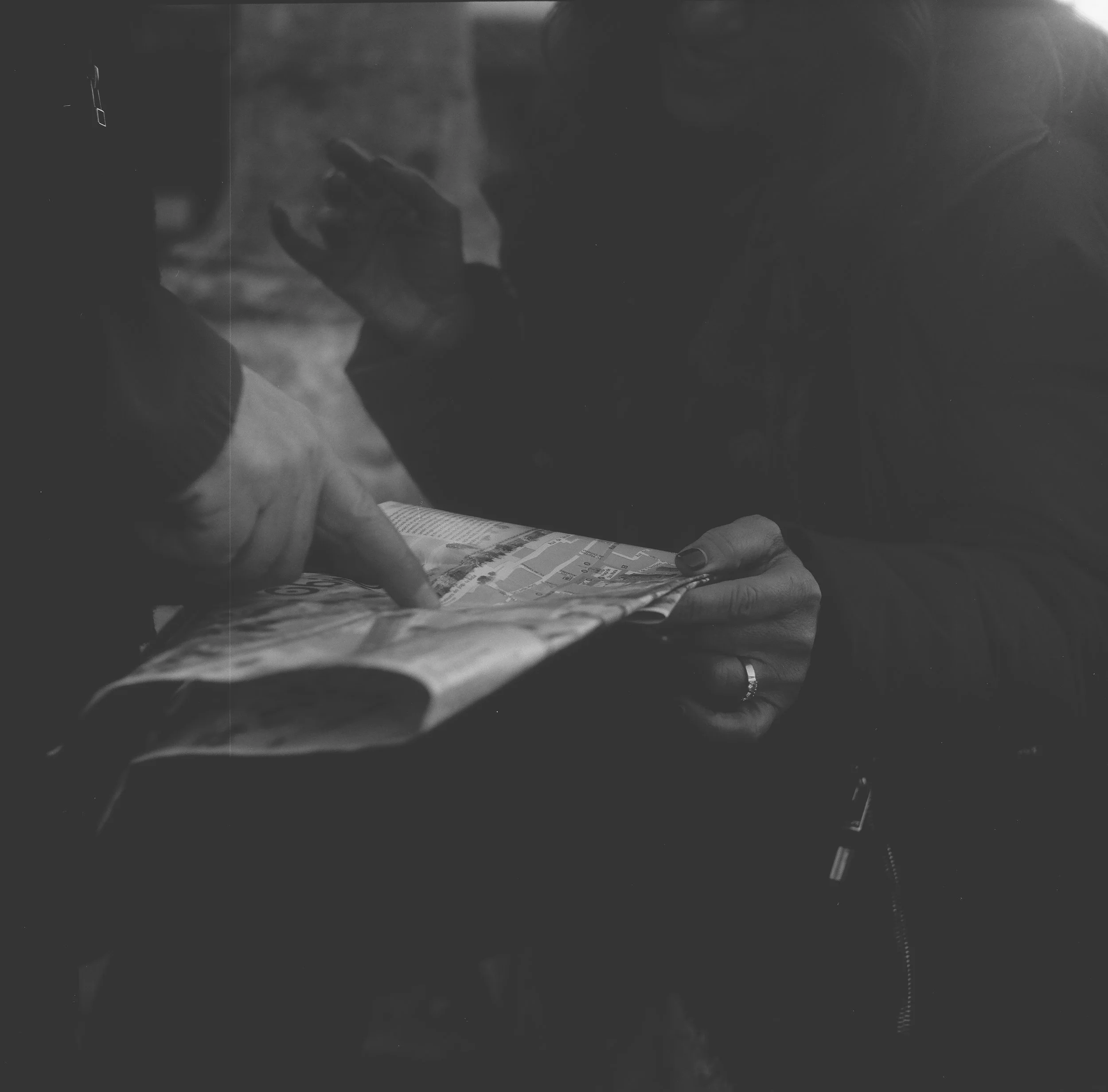 Black and white film capture of travelers navigating a map. Representing the core product themes of direction, decision-making, and wayfinding.