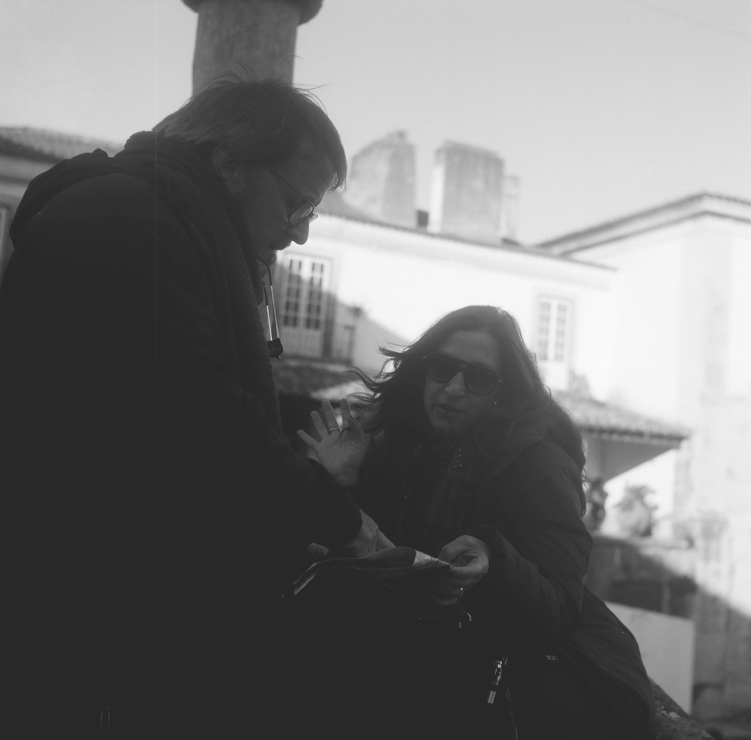Black and white film capture of travelers navigating a map. Representing the core product themes of direction, decision-making, and wayfinding.