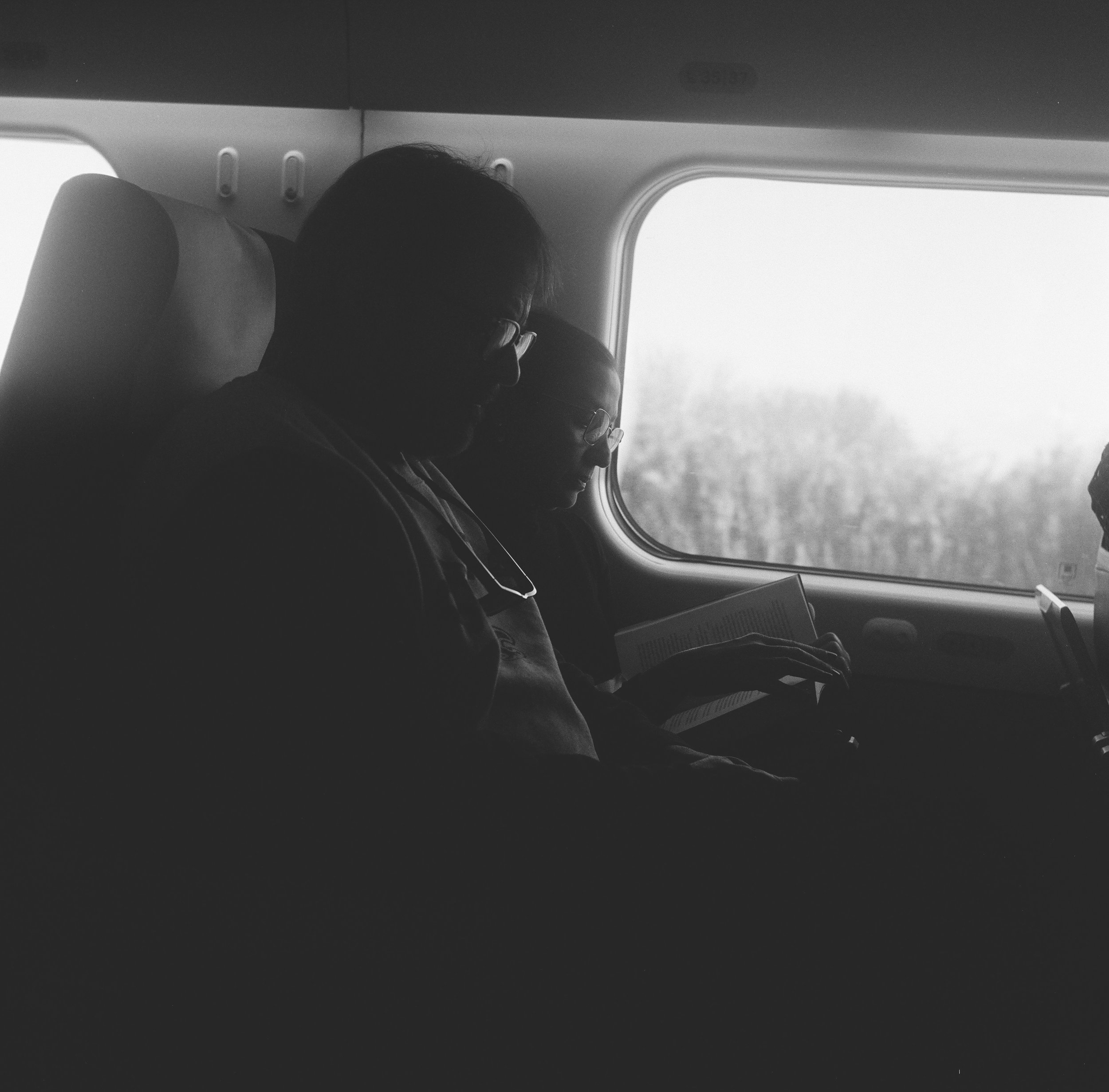 A quiet moment of focus captured on film. Two passengers reading side-by-side, illustrating the 'passive engagement' discussed in the Wavemng case study.