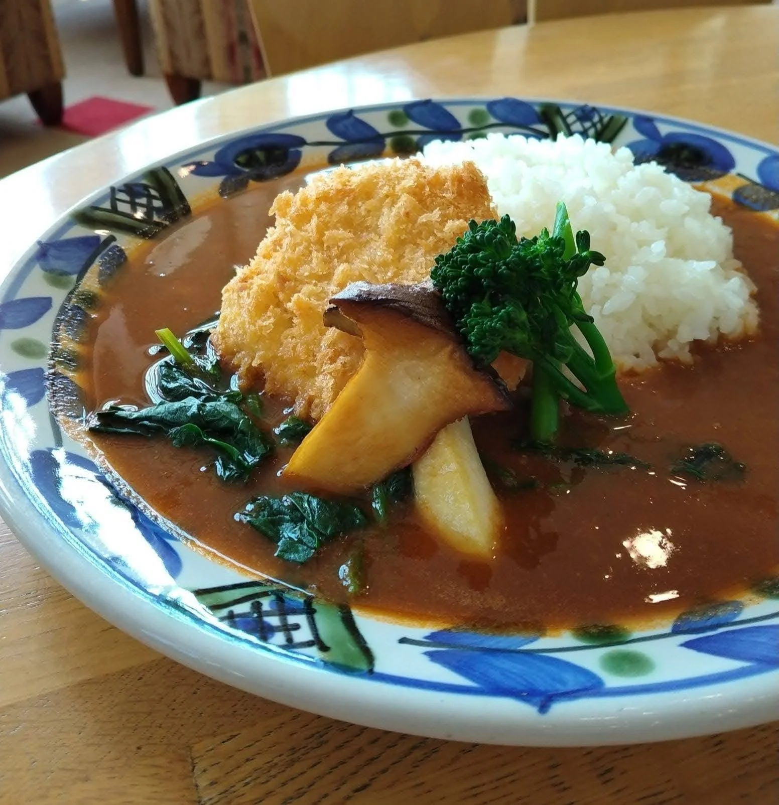 カレーライスに揚げた魚、ソテーしたマッシュルーム、かたくり粉にまぶした野菜とご飯が盛り付けられた皿