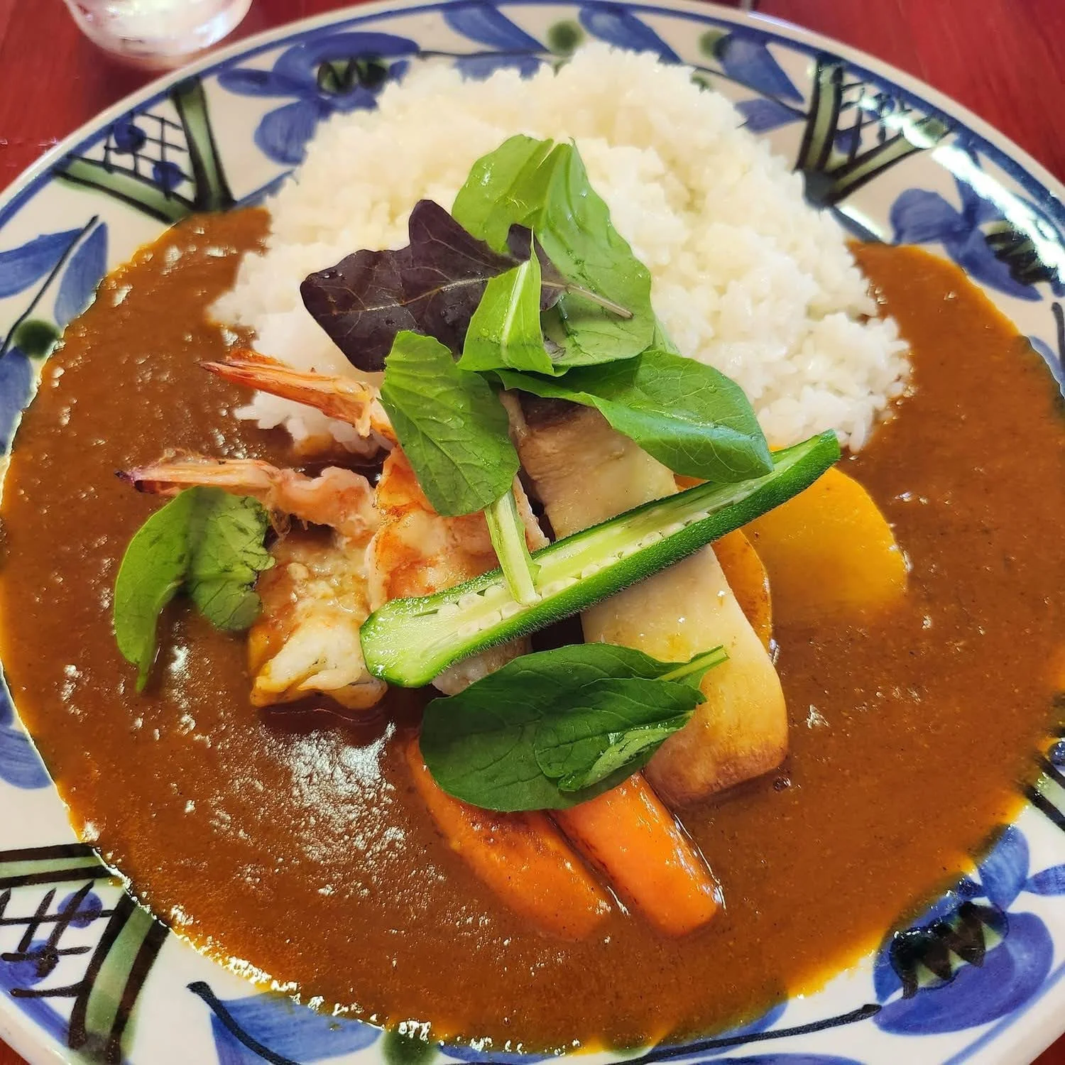 カレーライスにエビ、野菜、レタスやきゅうりのサラダが盛り付けられた料理