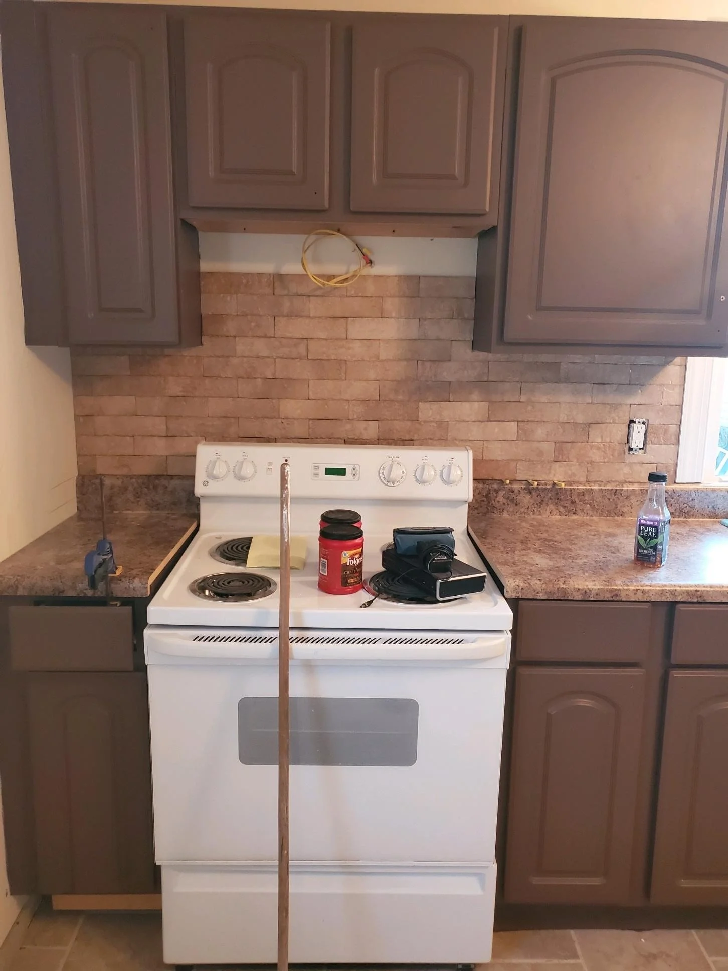 Kitchen renovation showing installed cabinets and tile backsplash before final cleanup.