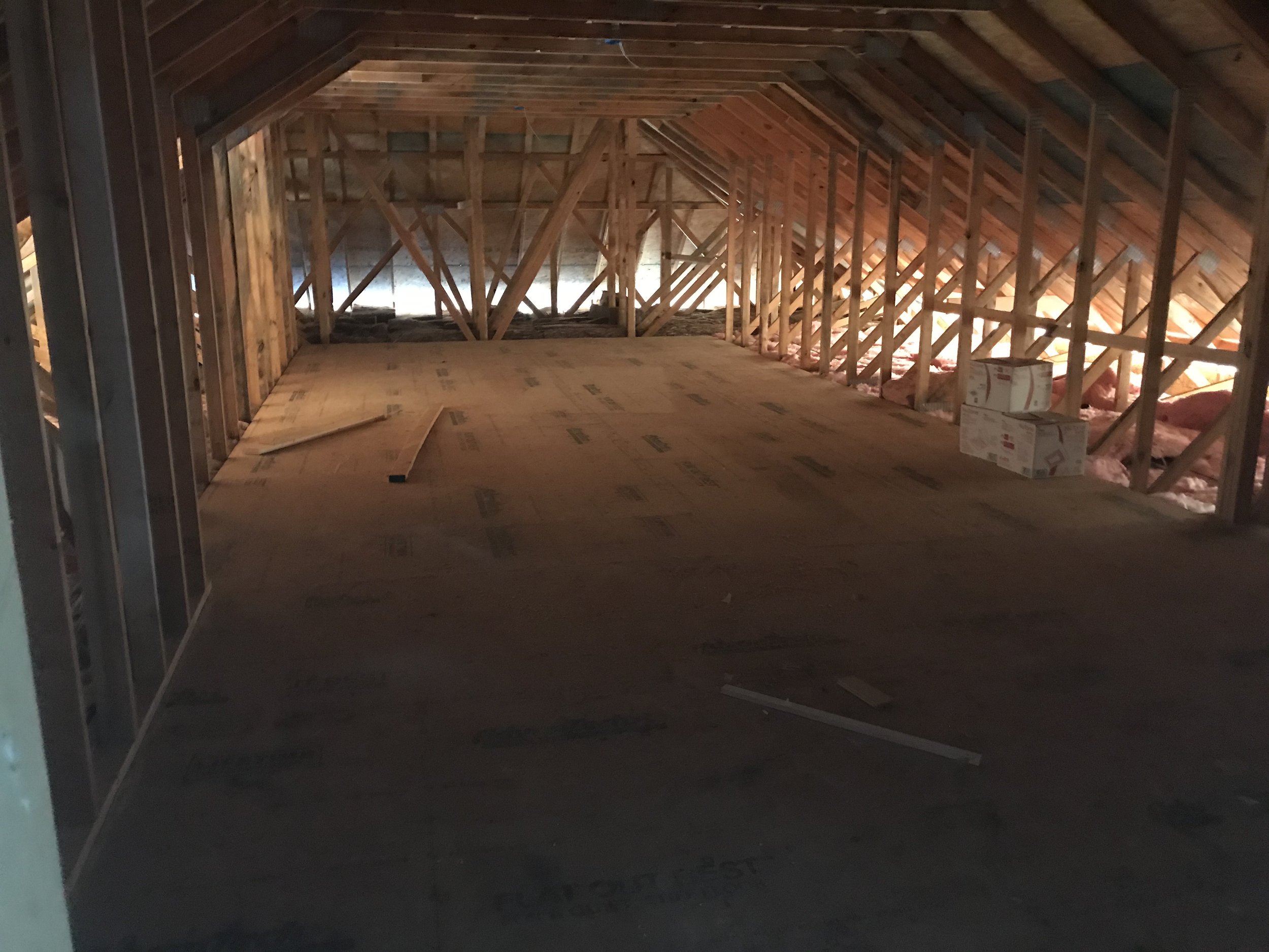 Attic framing and structural work during a residential renovation before insulation and drywall.