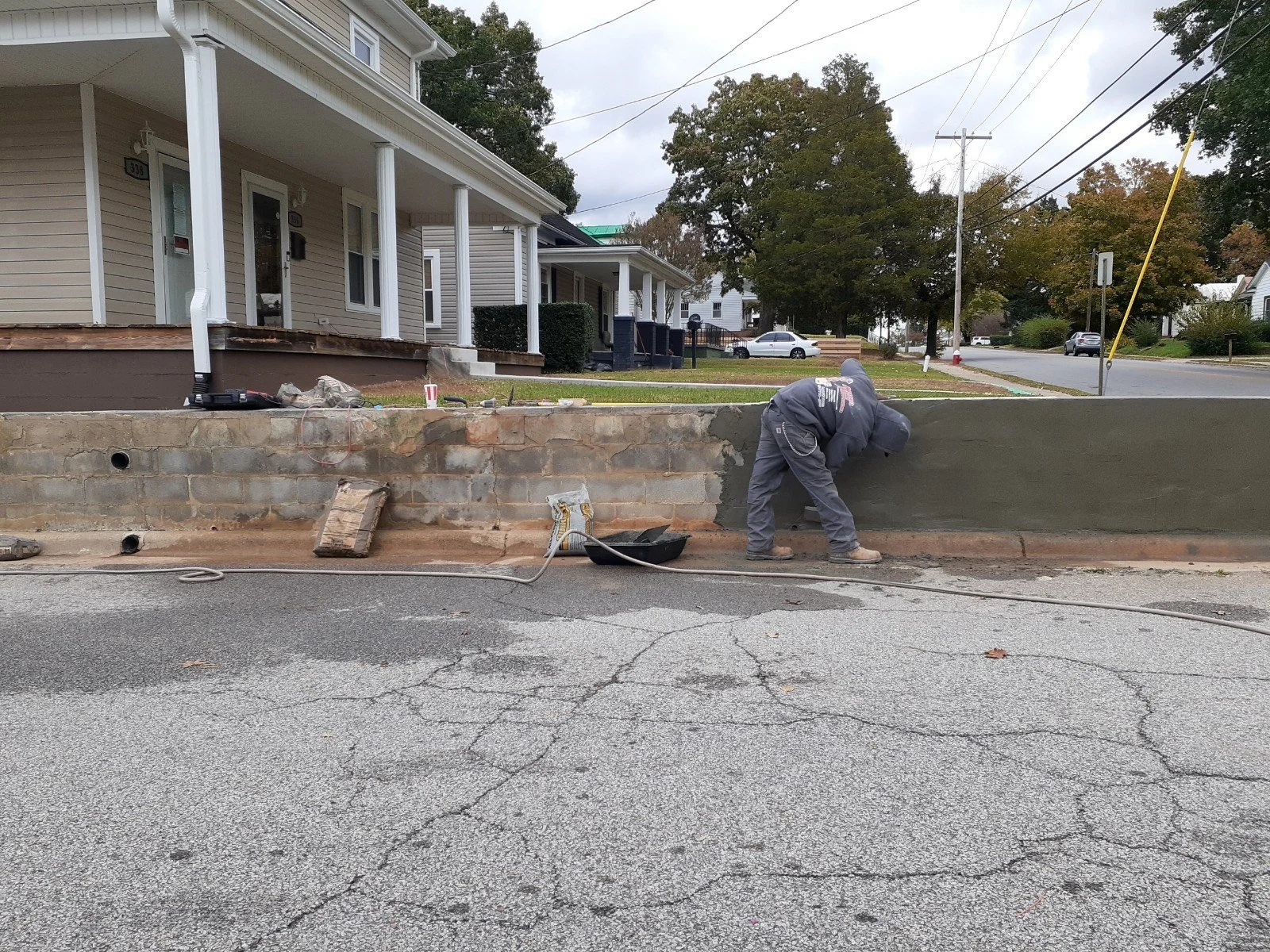 Exterior masonry work being completed along a residential property boundary.