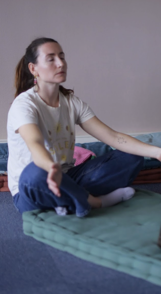 Femme méditant en position du lotus dans une pièce calme, assise sur un matelas vert.